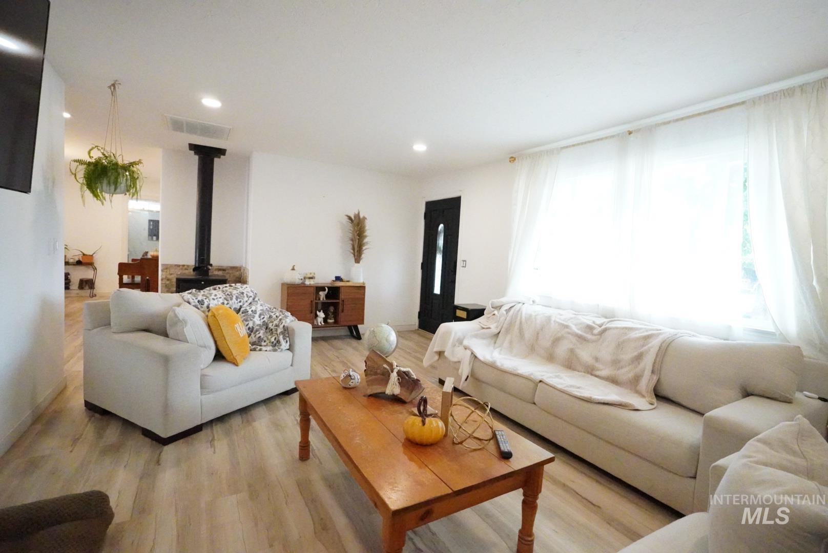Living room featuring a wood stove, light wood-style floors, and recessed lighting