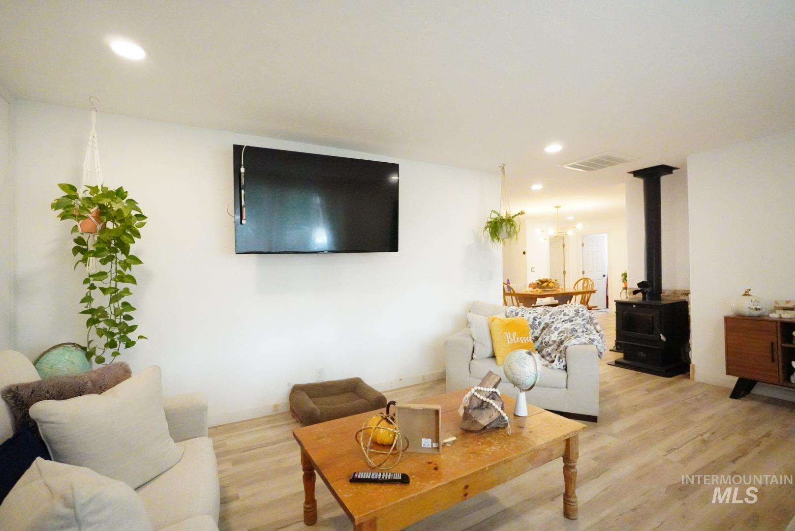 Living room featuring a wood stove, recessed lighting, and wood finished floors