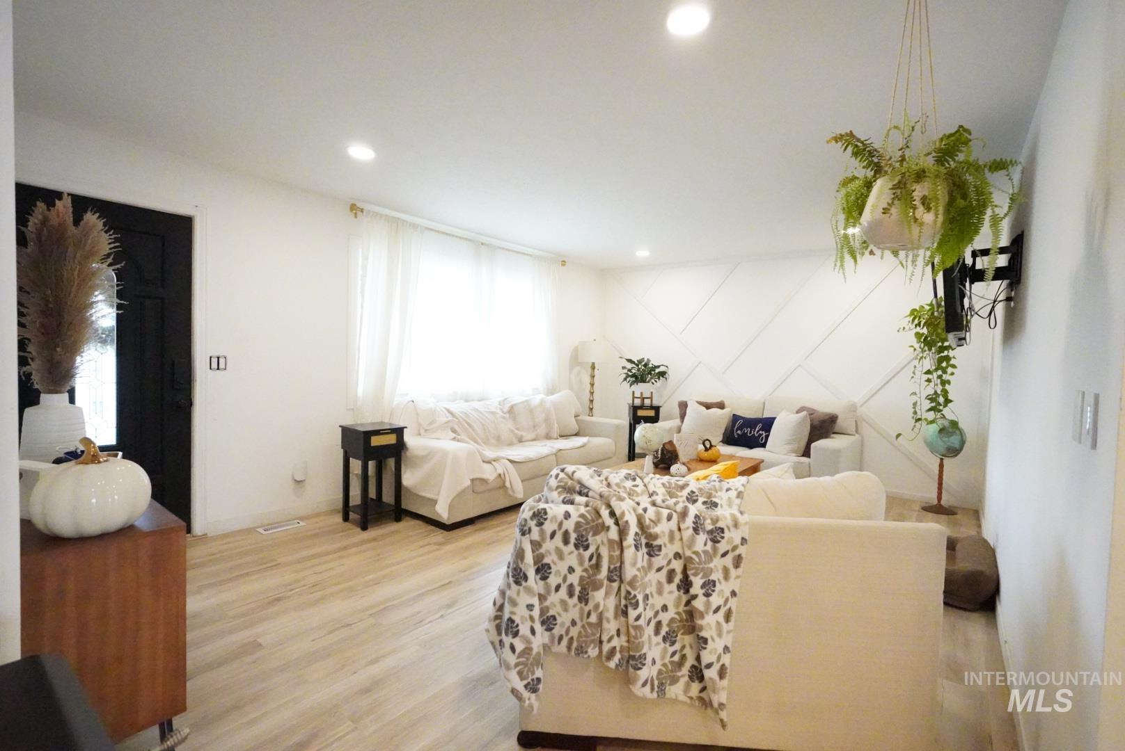 Living area with light wood-style flooring, recessed lighting, and a decorative wall