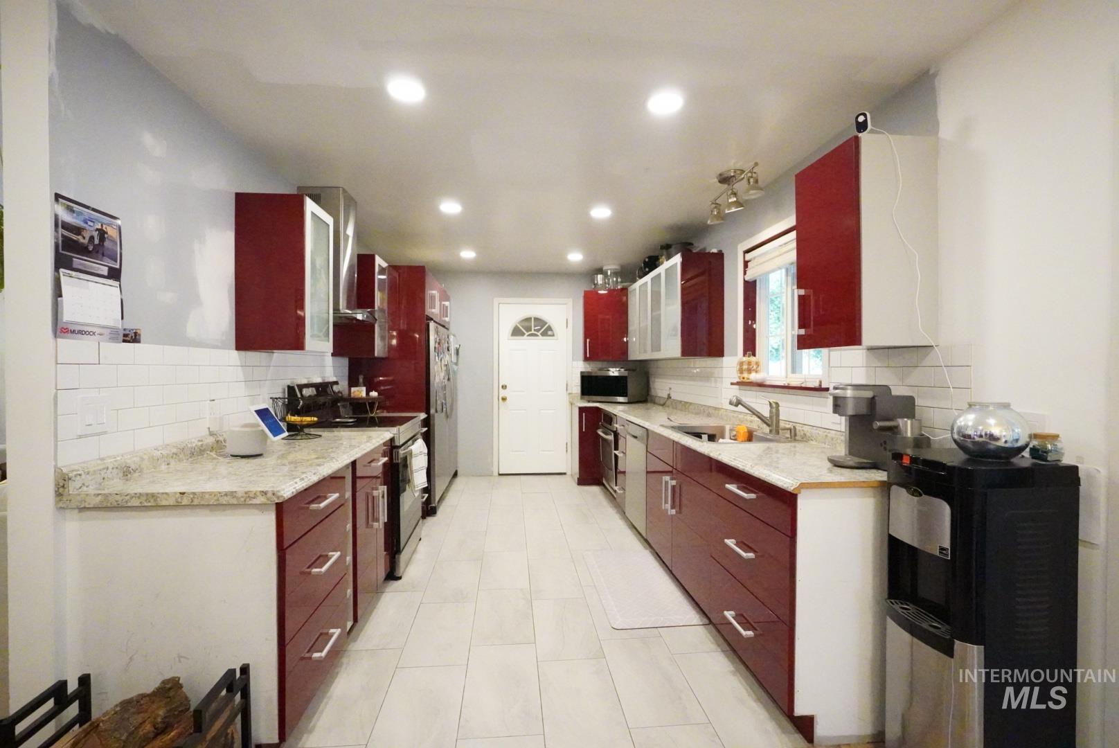 Kitchen with tasteful backsplash, appliances with stainless steel finishes, dark brown cabinets, light tile patterned flooring, and recessed lighting