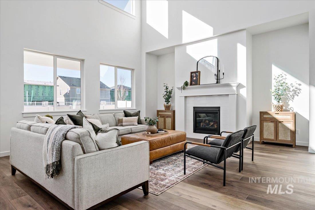 Living room featuring a brick fireplace, wood finished floors, and a high ceiling