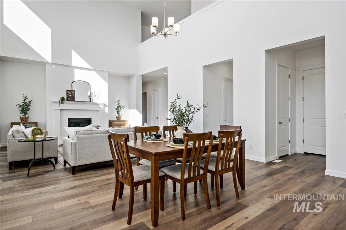 Dining area featuring a glass covered fireplace, wood finished floors, a towering ceiling, and a chandelier
