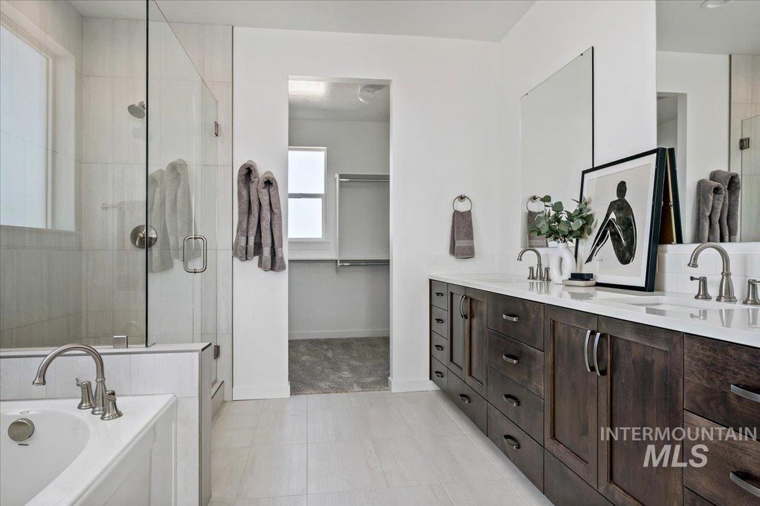 Bathroom featuring a stall shower, double vanity, a bath, light tile patterned floors, and a spacious closet