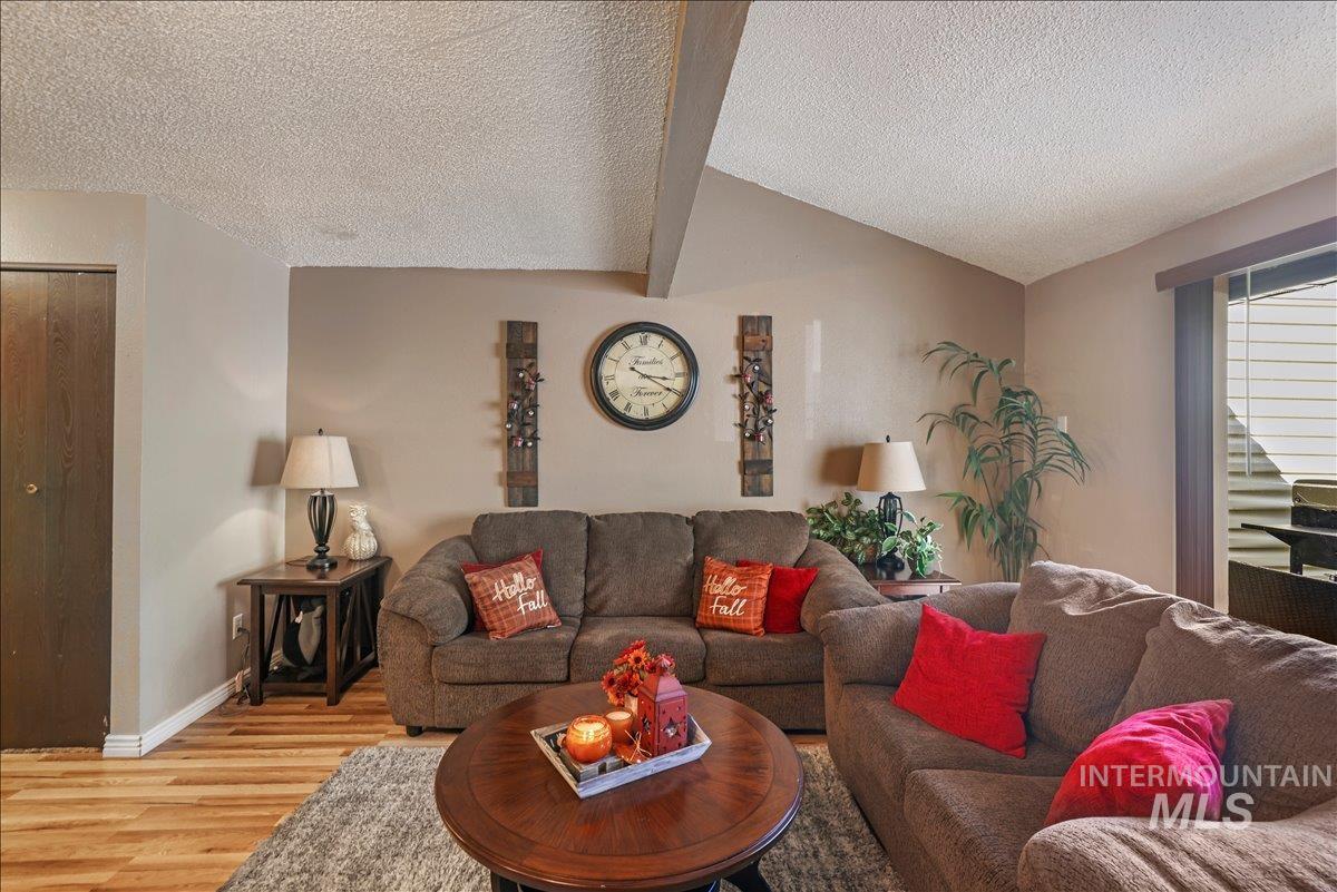 Living room featuring vaulted ceiling, wood finished floors, and a textured ceiling