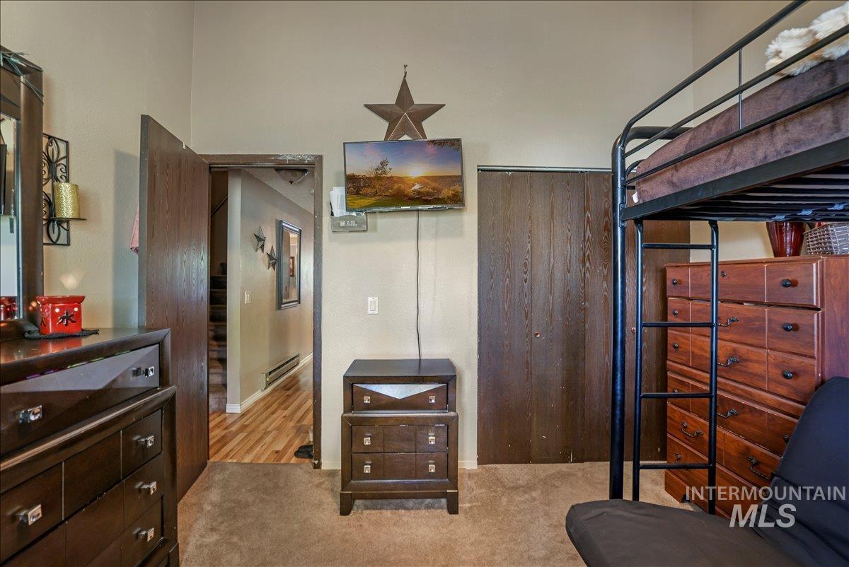 Bedroom with light carpet and baseboard heating