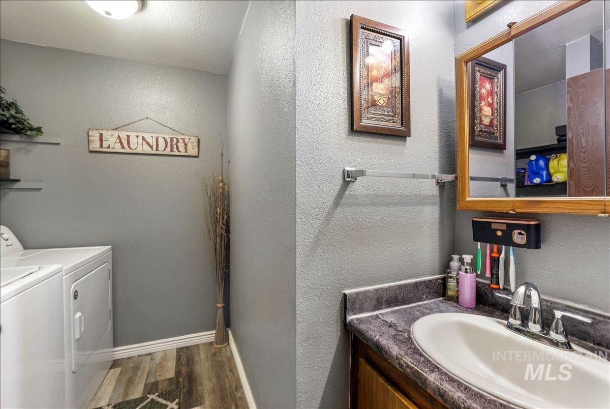 Bathroom with a textured wall, dark wood-style flooring, vanity, and washer and clothes dryer