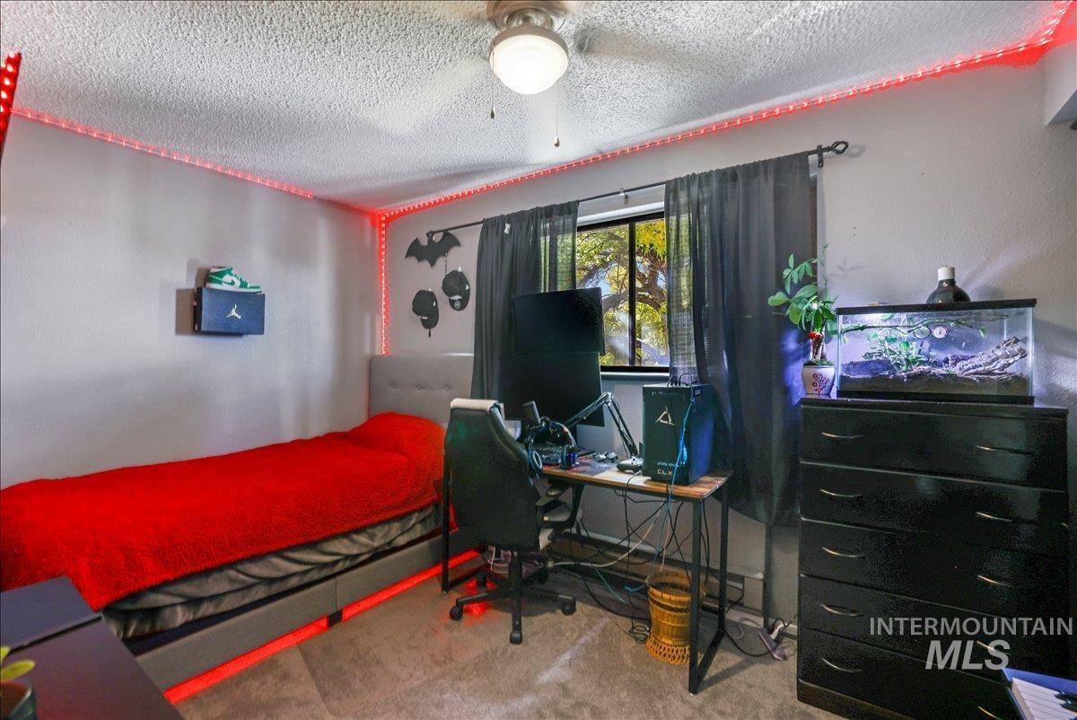 Carpeted bedroom with a textured ceiling and a desk