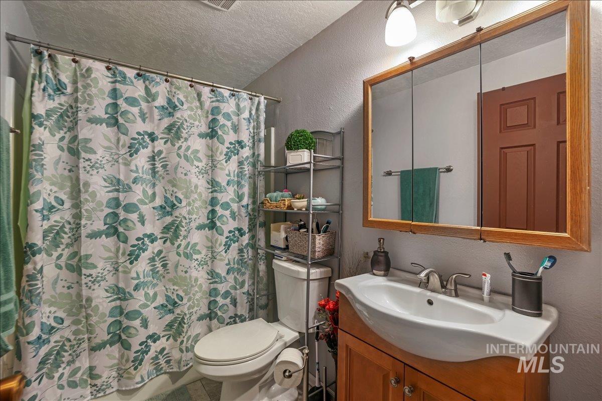 Bathroom featuring a textured wall, a textured ceiling, vanity, and a shower with shower curtain