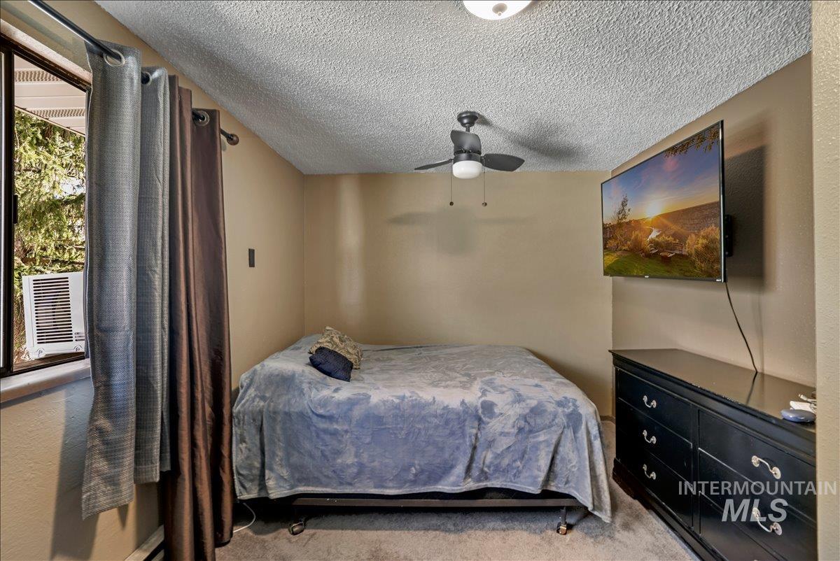 Carpeted bedroom featuring a textured ceiling and ceiling fan