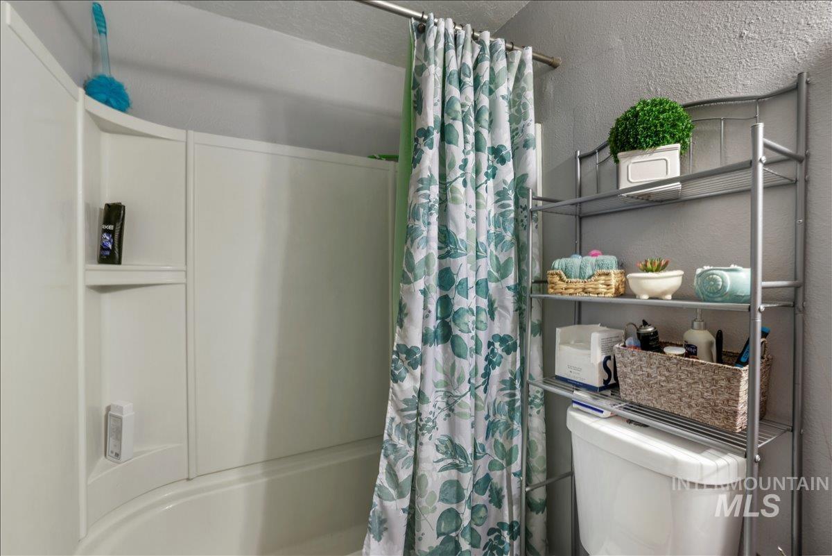 Full bathroom with a textured wall and shower / bath combo