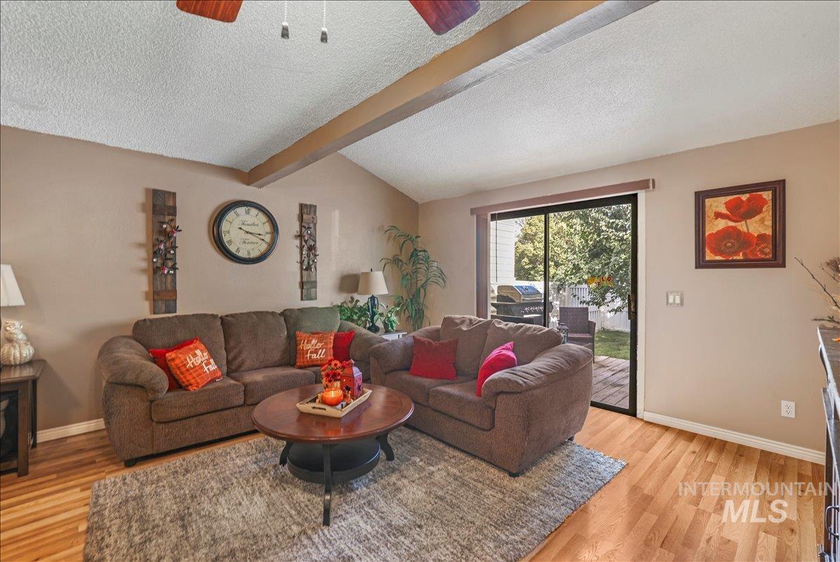 Living room with a textured ceiling, light wood-style floors, and a ceiling fan