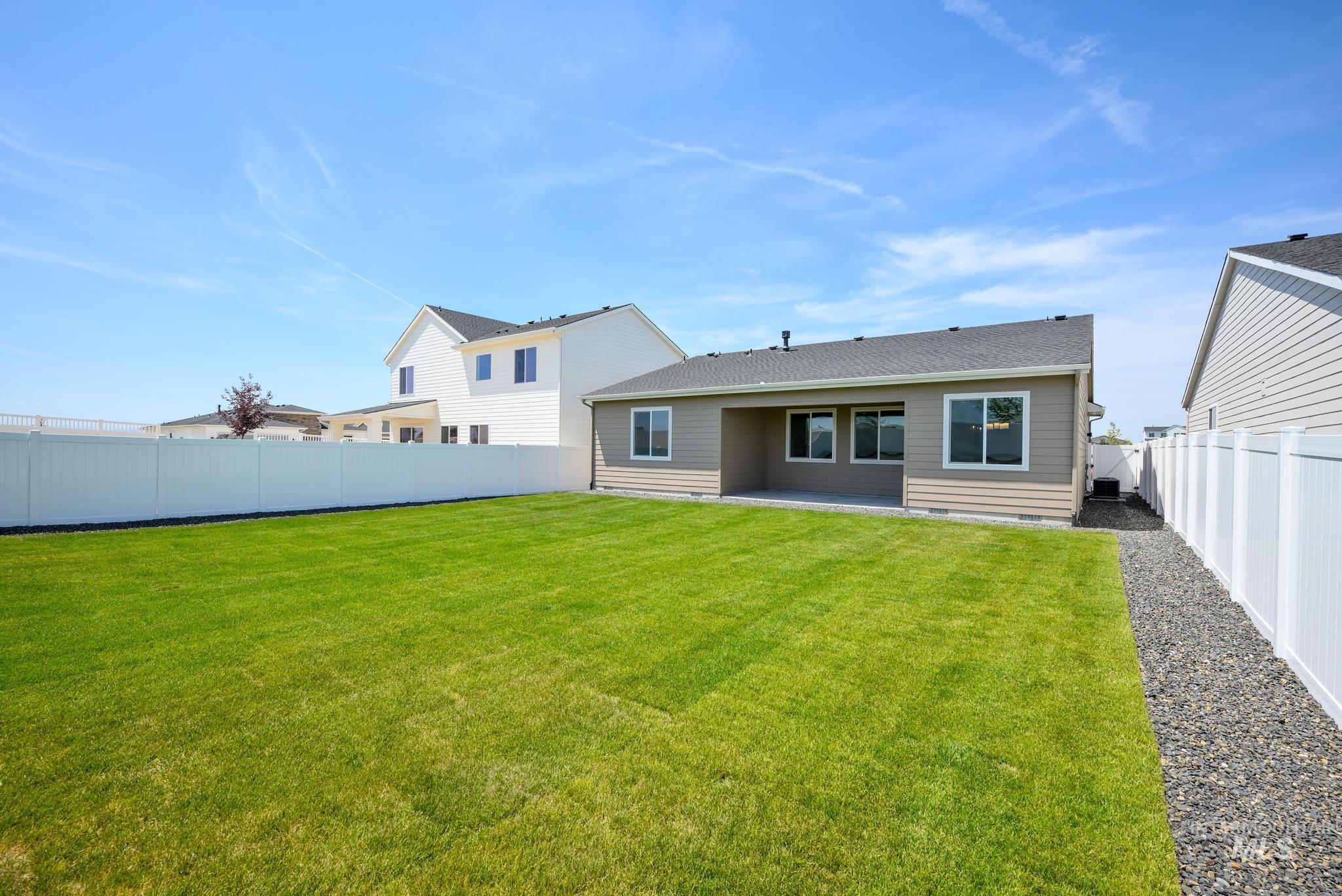 Rear view of house featuring a patio area, a fenced backyard, and a shingled roof