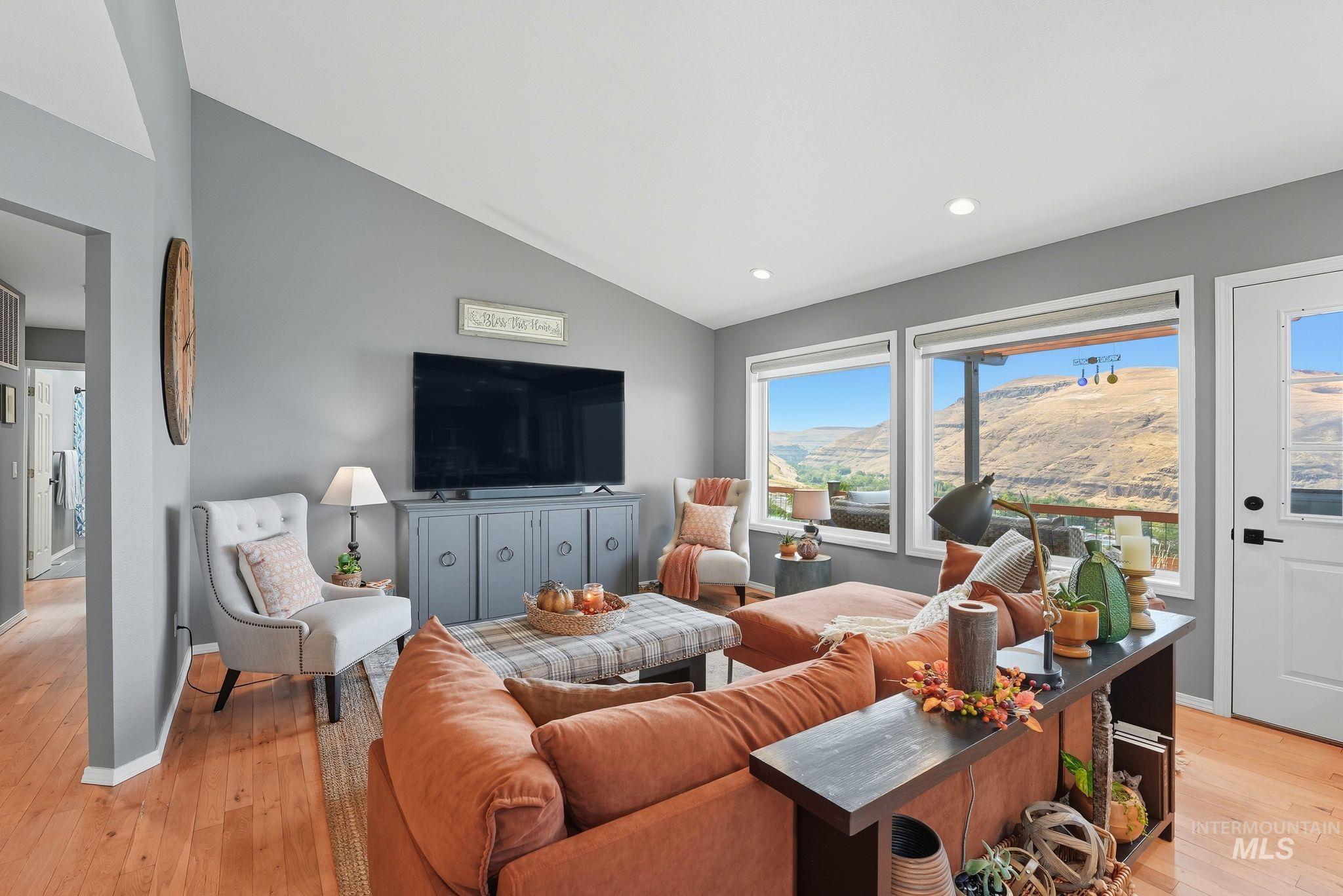 Living room featuring vaulted ceiling, light wood-style floors, and recessed lighting