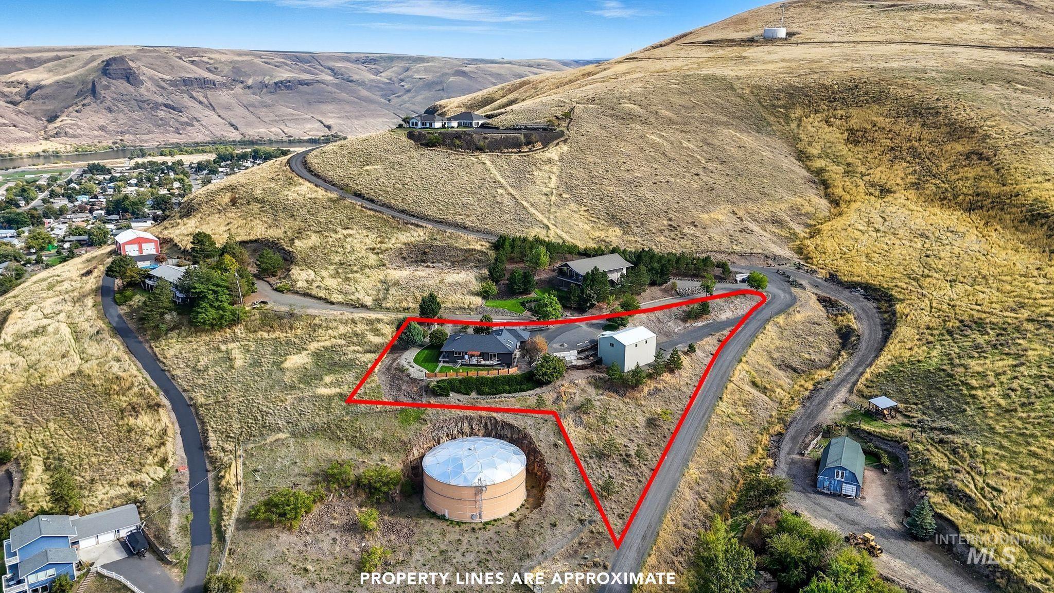 Aerial view of property and surrounding area with property parcel outlined and a mountain backdrop