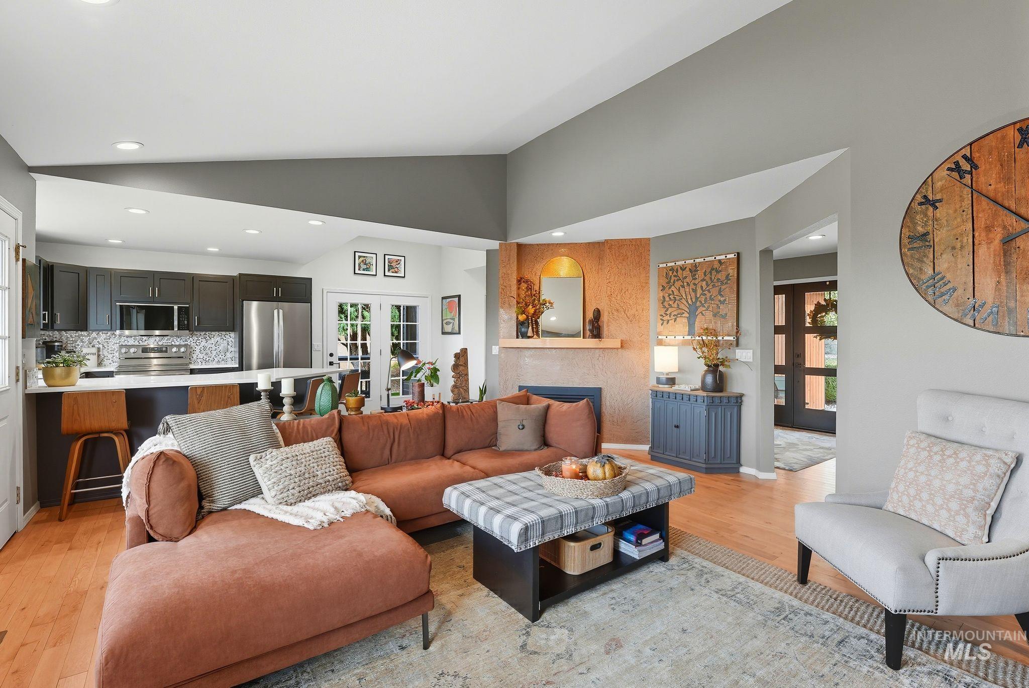 Living area featuring french doors, light wood-type flooring, lofted ceiling, recessed lighting, and a fireplace