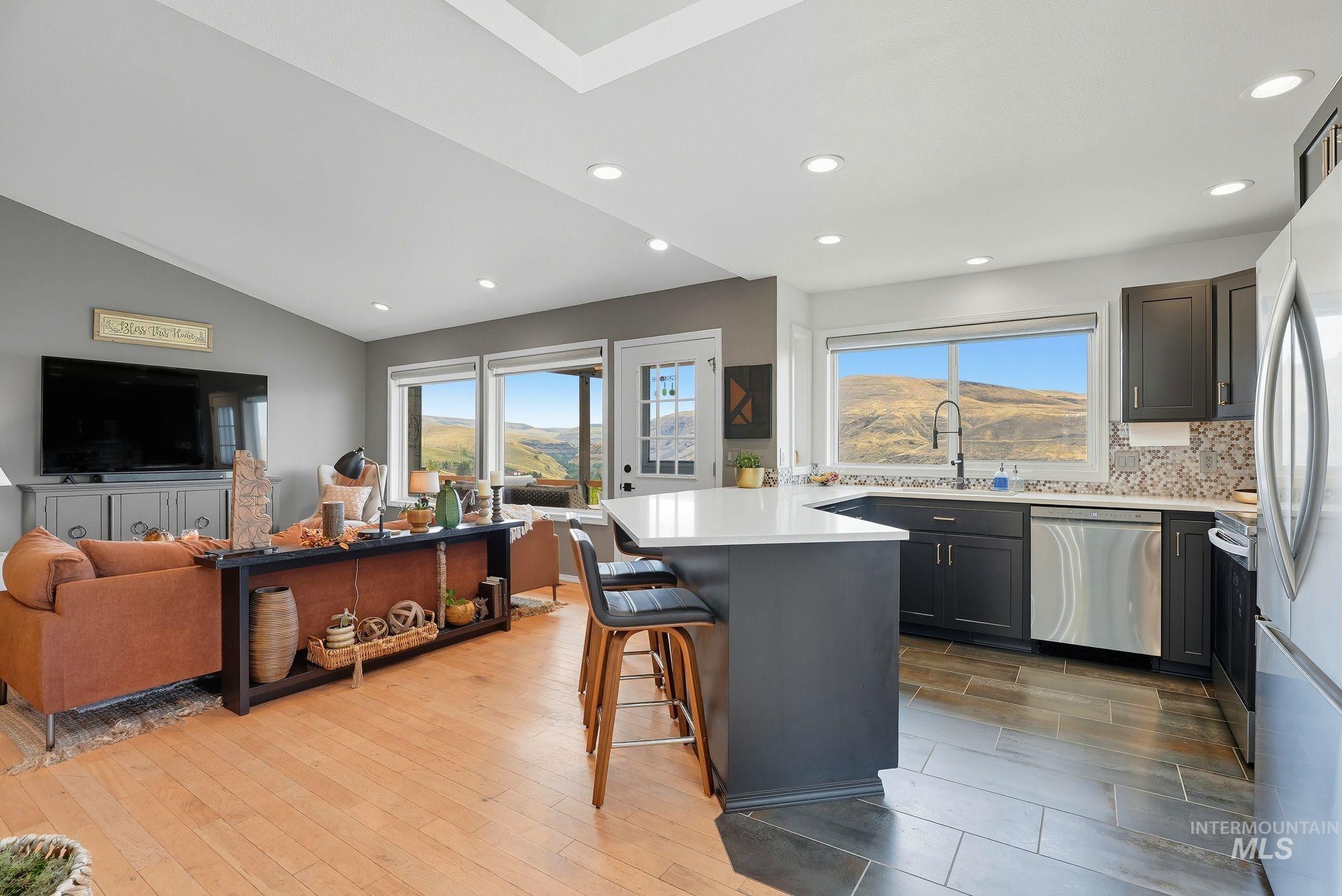 Kitchen featuring a peninsula, light wood finished floors, a breakfast bar, appliances with stainless steel finishes, and tasteful backsplash