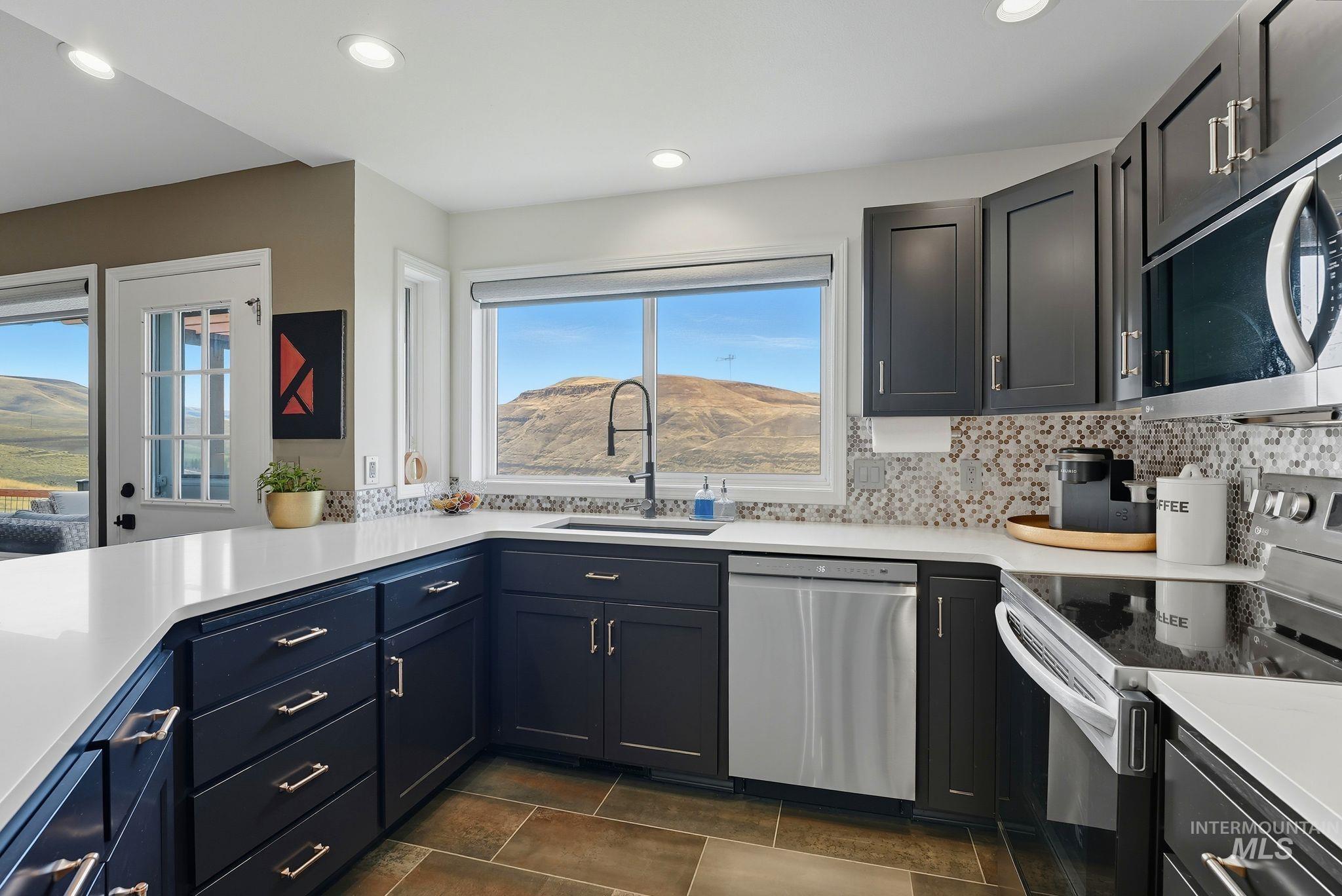 Kitchen with stainless steel appliances, a mountain view, recessed lighting, backsplash, and light stone counters