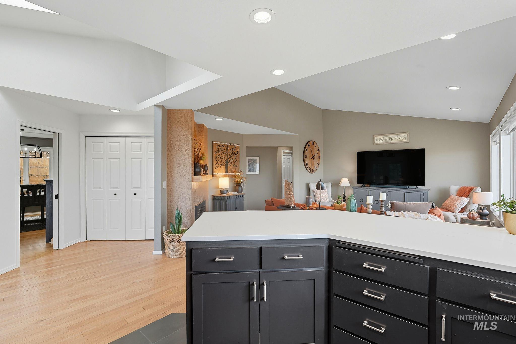 Kitchen featuring recessed lighting, open floor plan, vaulted ceiling, light wood finished floors, and light stone countertops