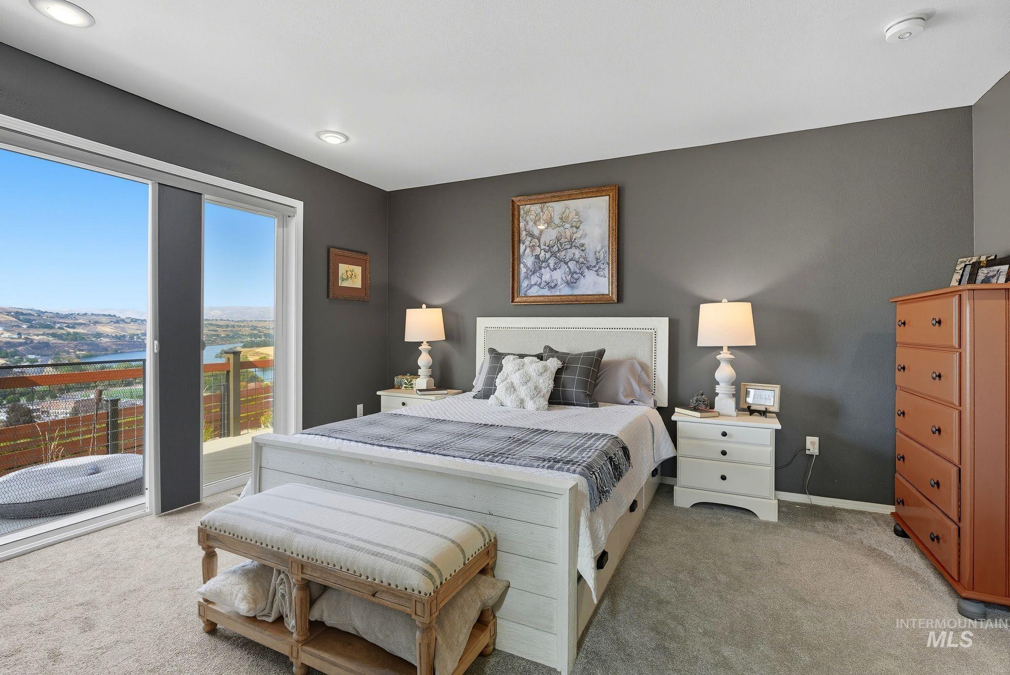 Bedroom featuring access to exterior, light colored carpet, a water view, and recessed lighting
