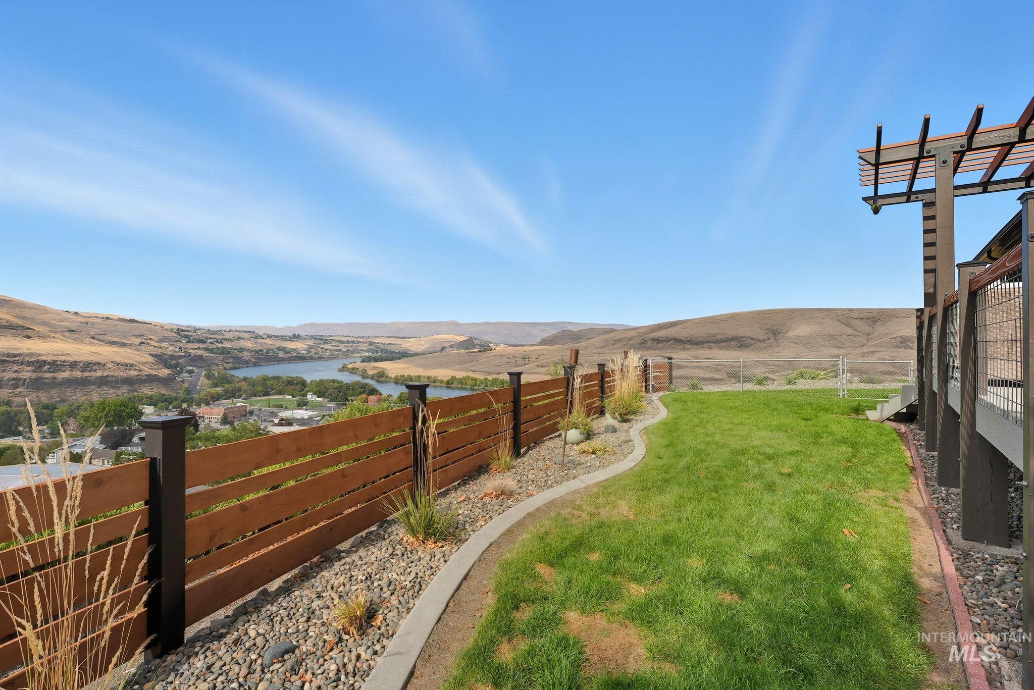 Fenced backyard with a water and mountain view and a view of rural / pastoral area