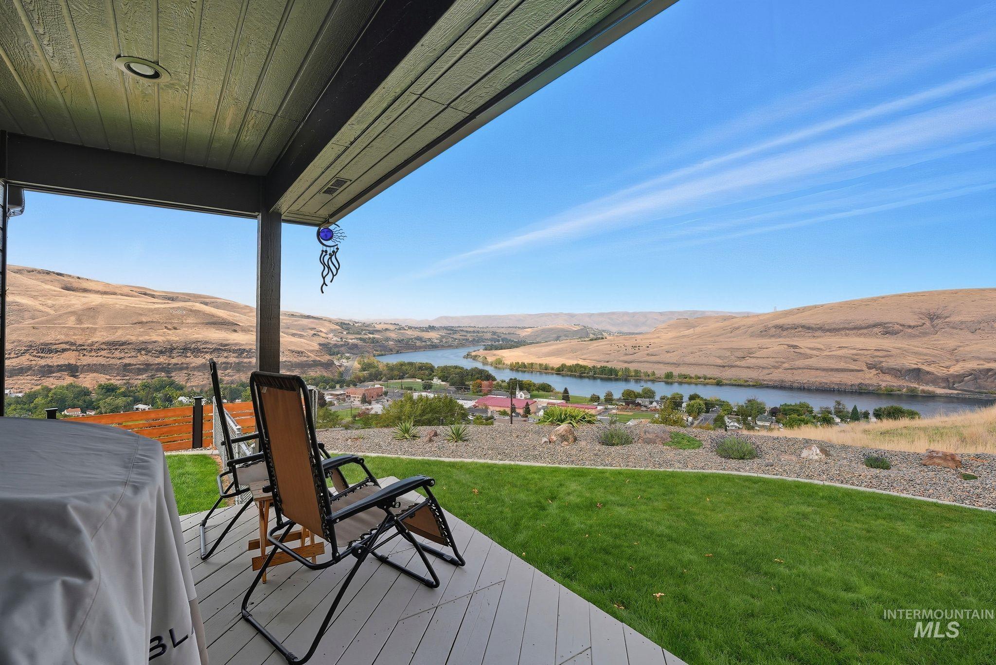 Wooden terrace with a water view, area for grilling, and a lawn