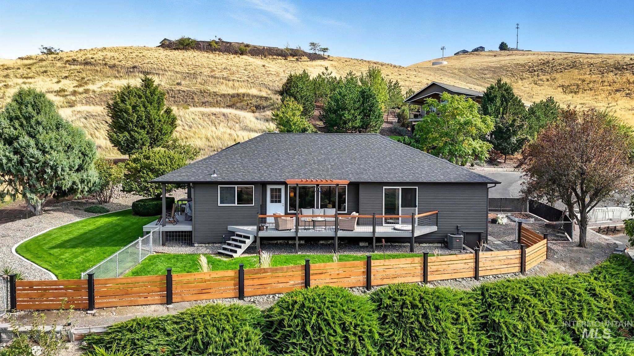 Rear view of property featuring a deck, a fenced backyard, a shingled roof, and an outdoor living space