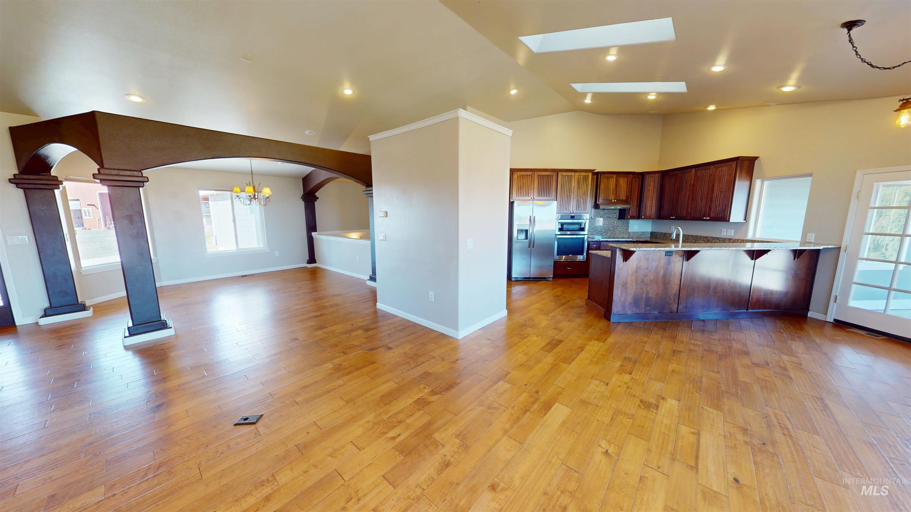 Kitchen featuring decorative light fixtures, plenty of natural light, a chandelier, open floor plan, and lofted ceiling