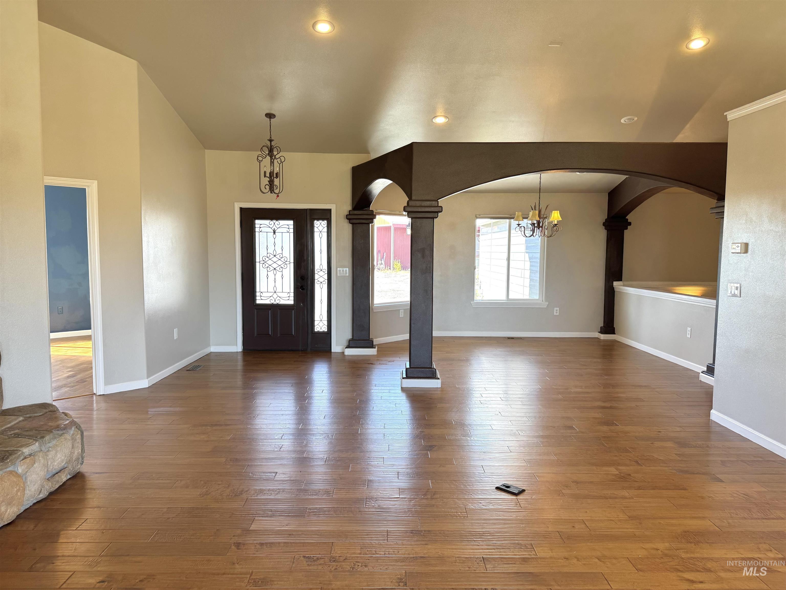 Entryway with a chandelier, dark wood-style floors, arched walkways, ornate columns, and recessed lighting
