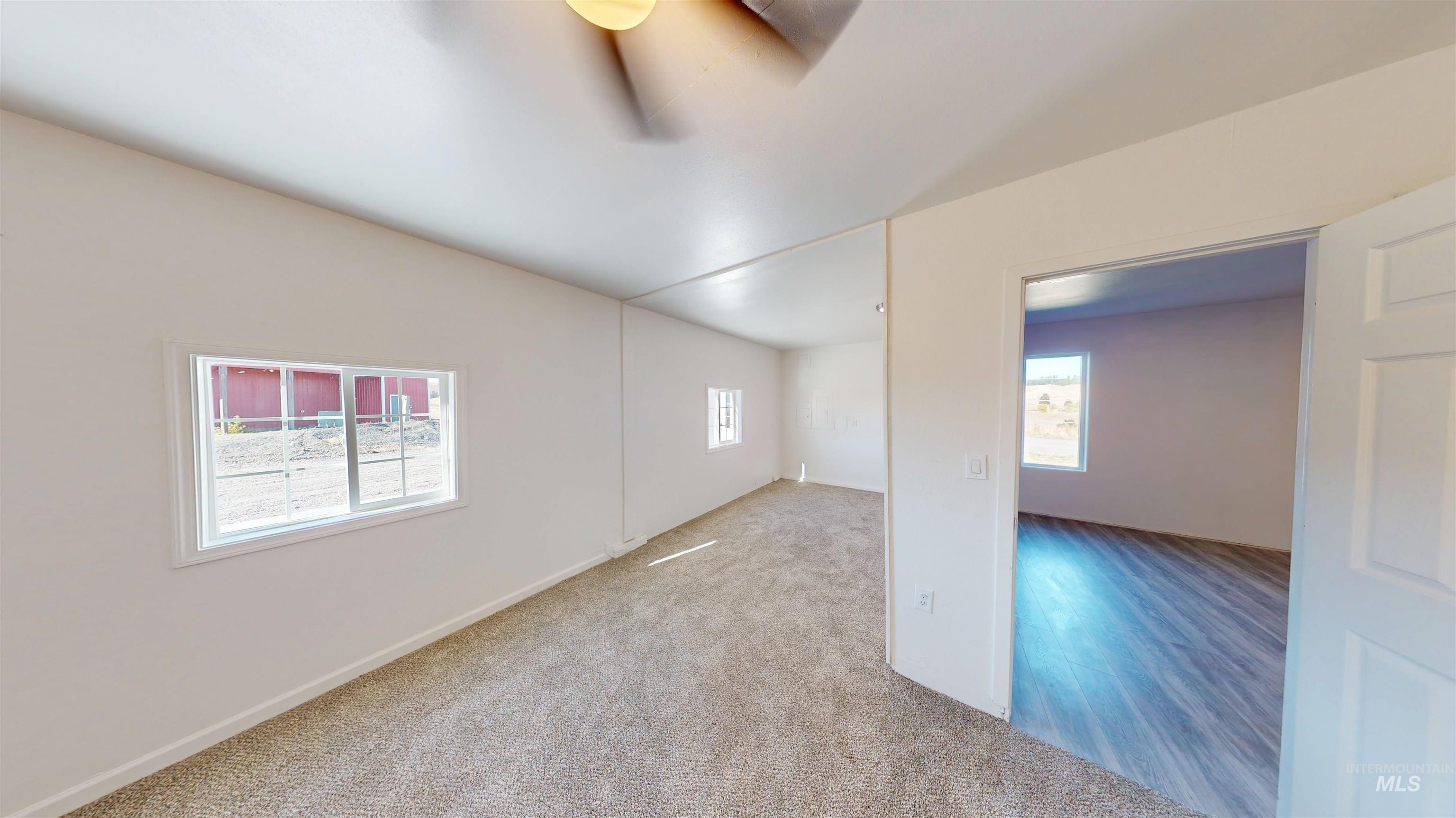 Carpeted spare room with ceiling fan and baseboards