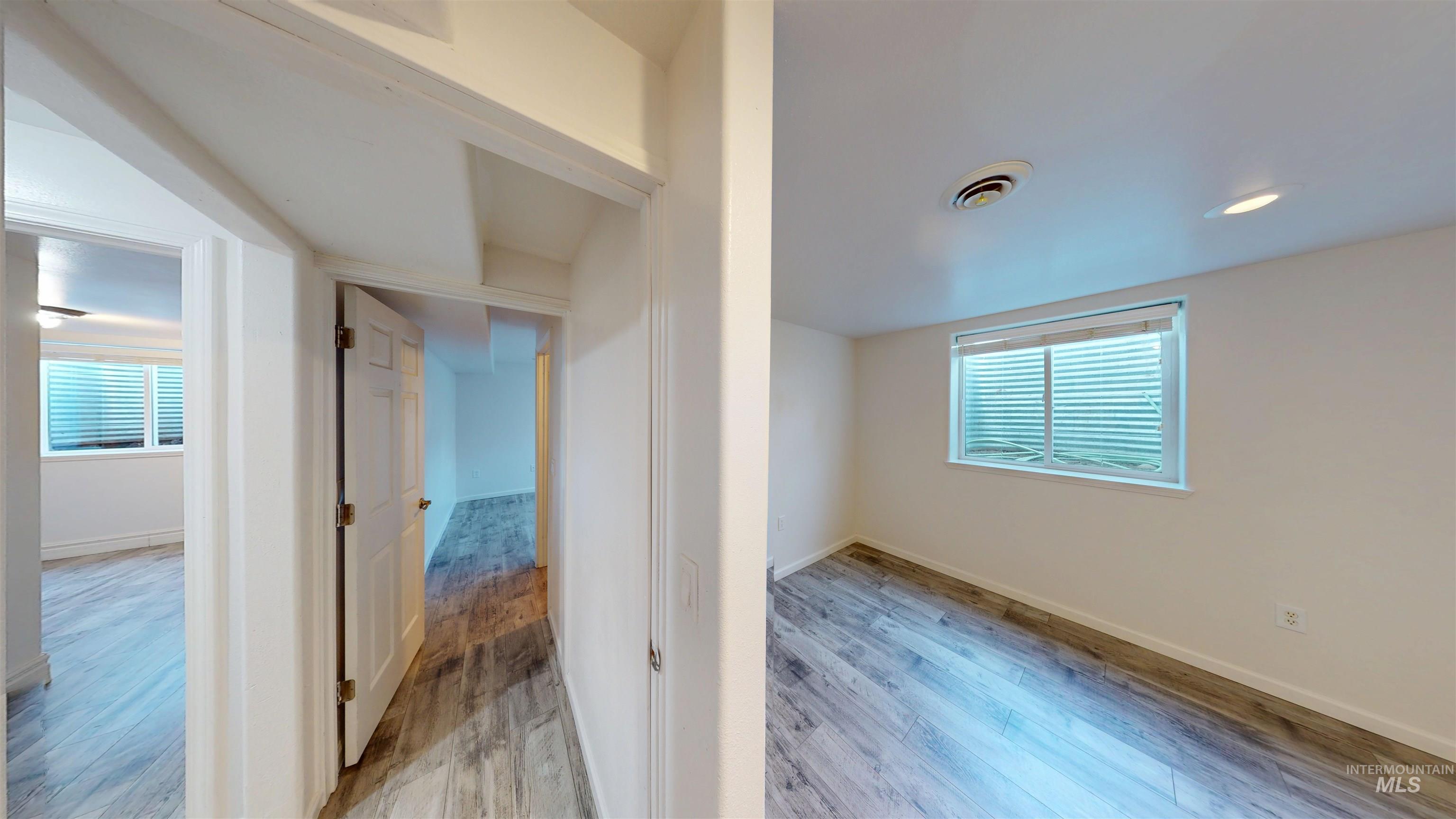 Corridor with light wood-type flooring and baseboards