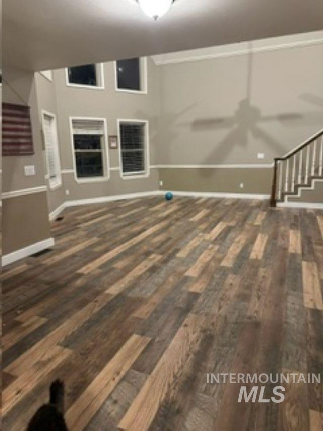 Unfurnished living room with stairway, dark wood-style floors, and ceiling fan