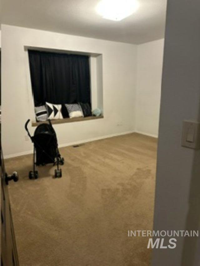 Empty room with light colored carpet and baseboards