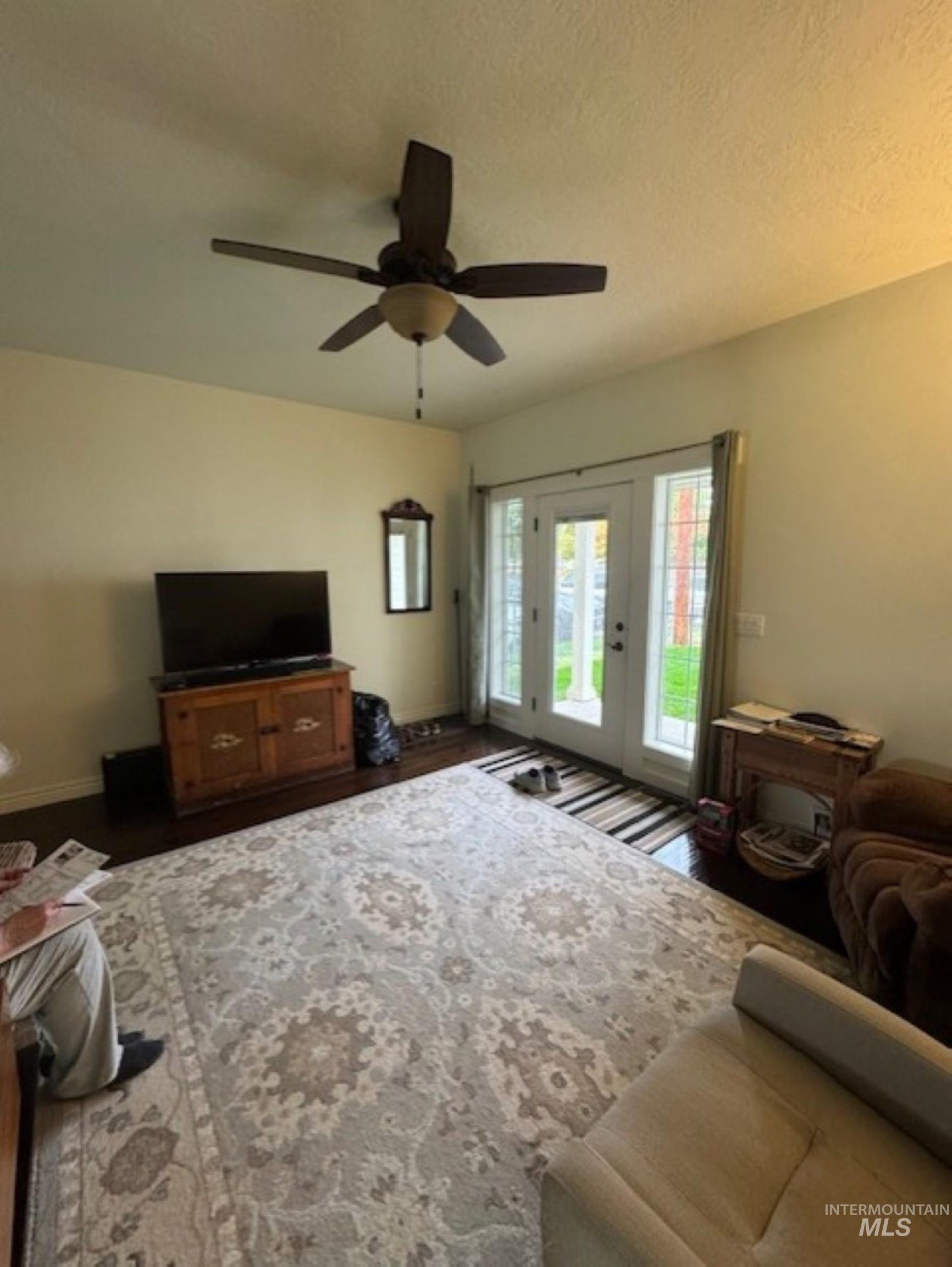 Living area with a textured ceiling, wood finished floors, and a ceiling fan