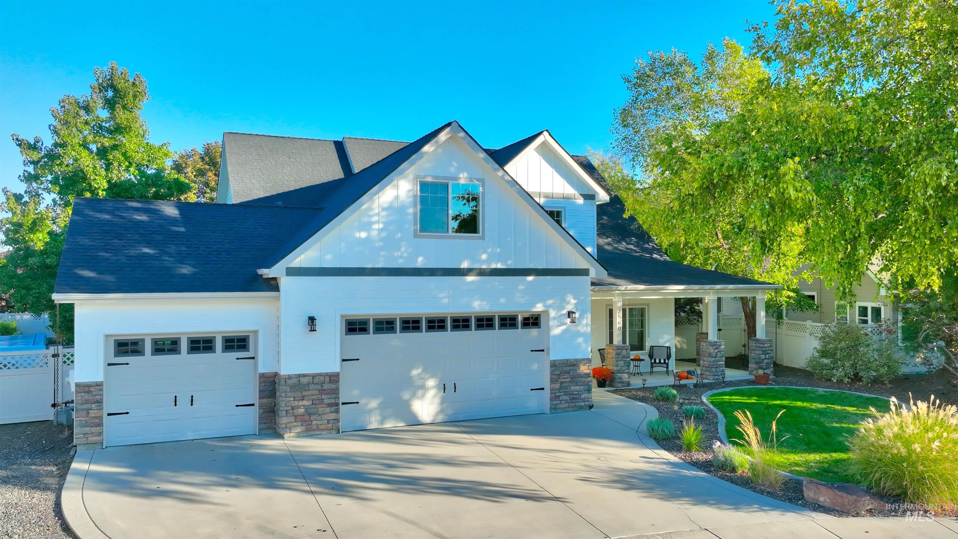 View of front of home with stone siding, a porch, driveway, and board and batten siding