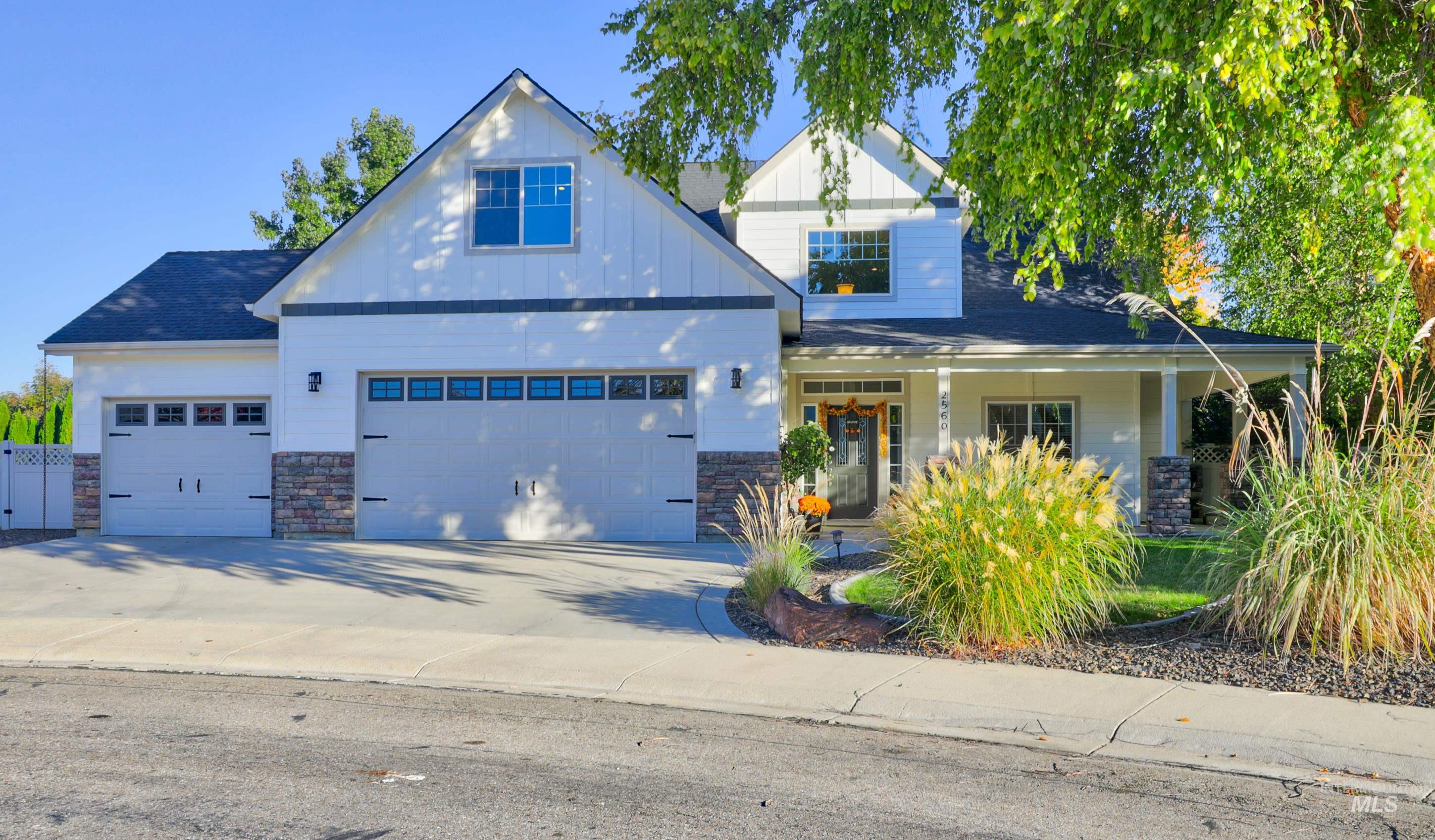 View of front of house with a porch, stone siding, concrete driveway, and board and batten siding