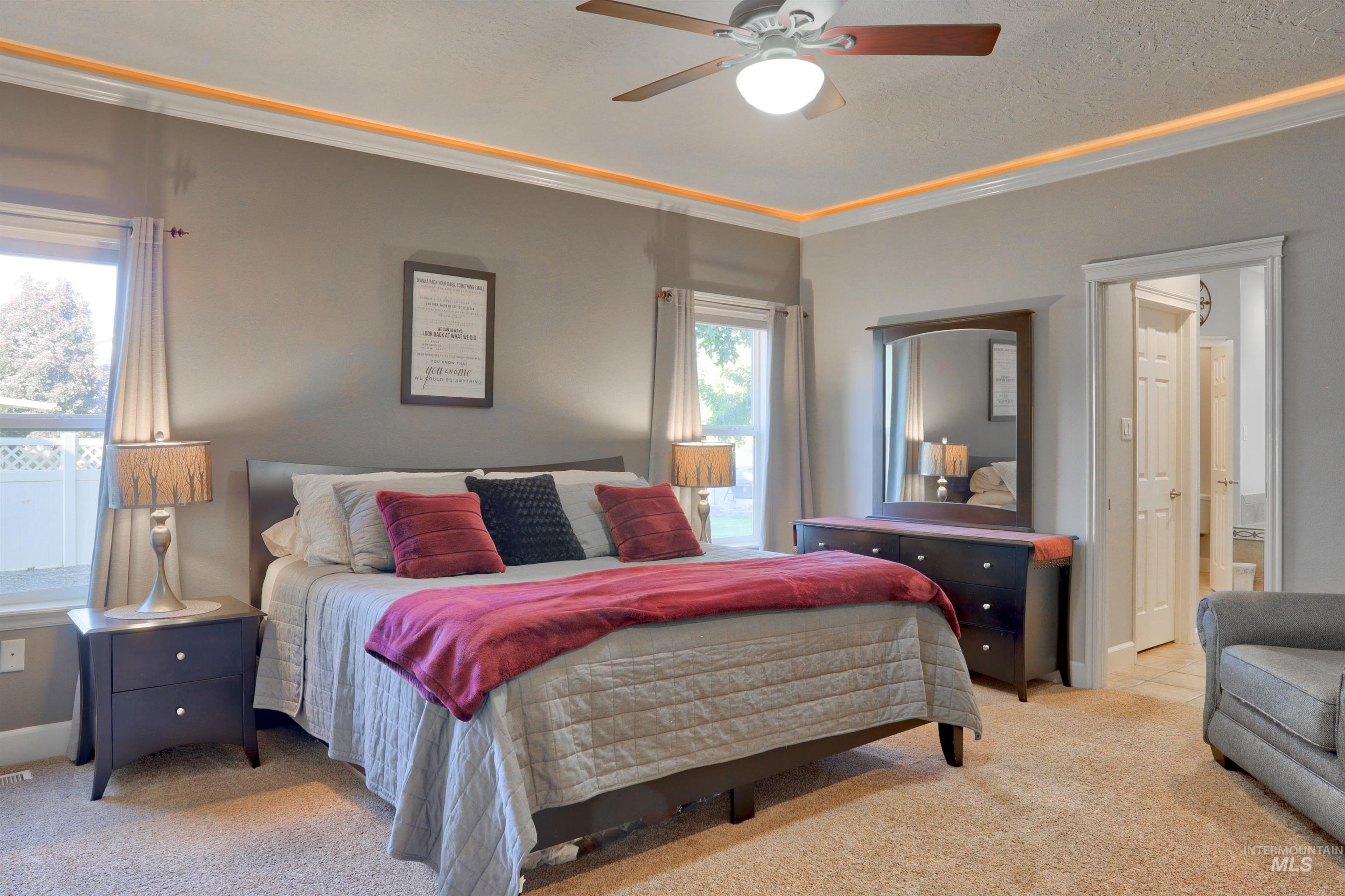 Carpeted bedroom featuring crown molding, ceiling fan, and a textured ceiling
