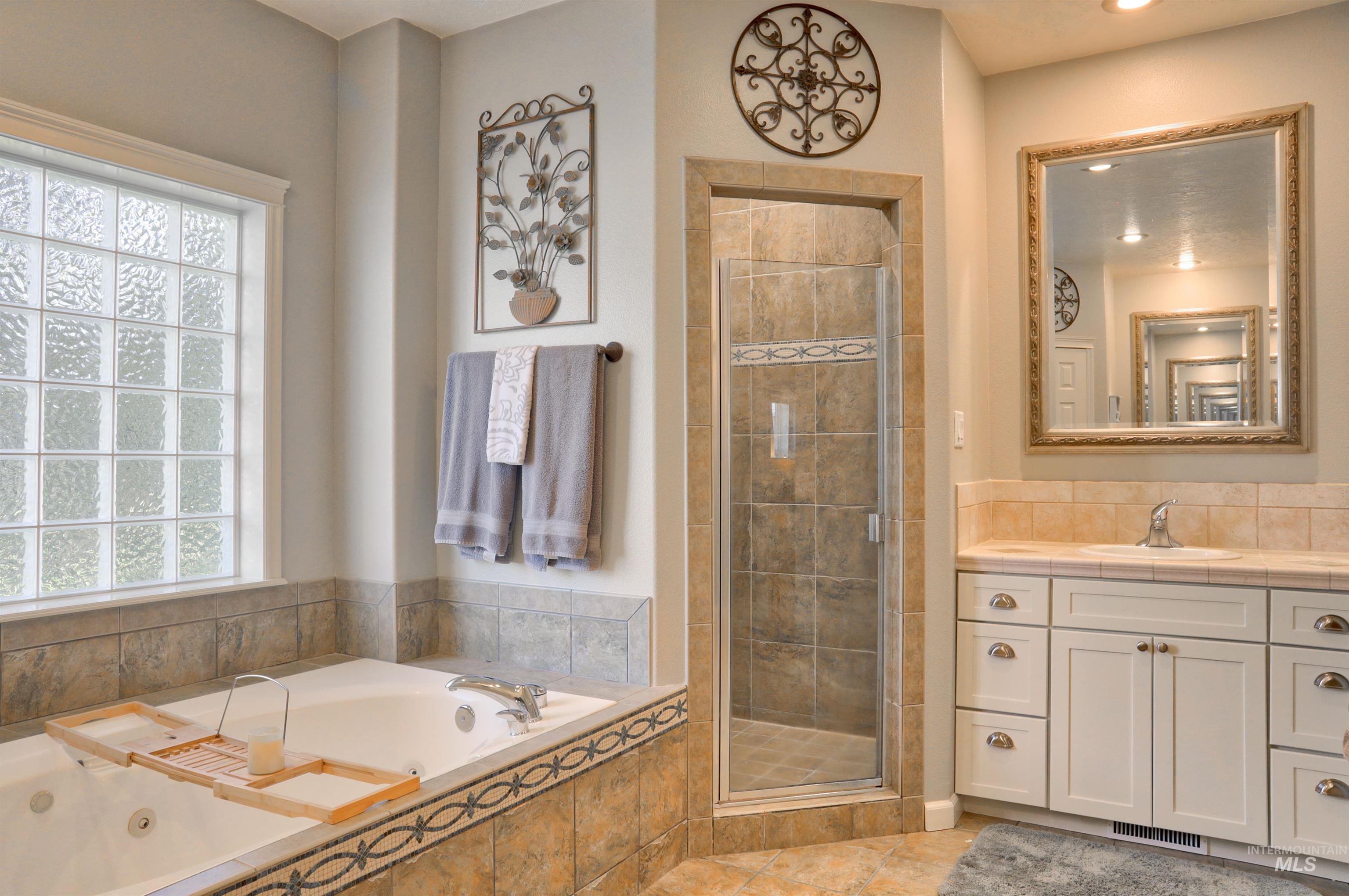 Full bathroom with vanity, a stall shower, a tub with jets, and light tile patterned flooring