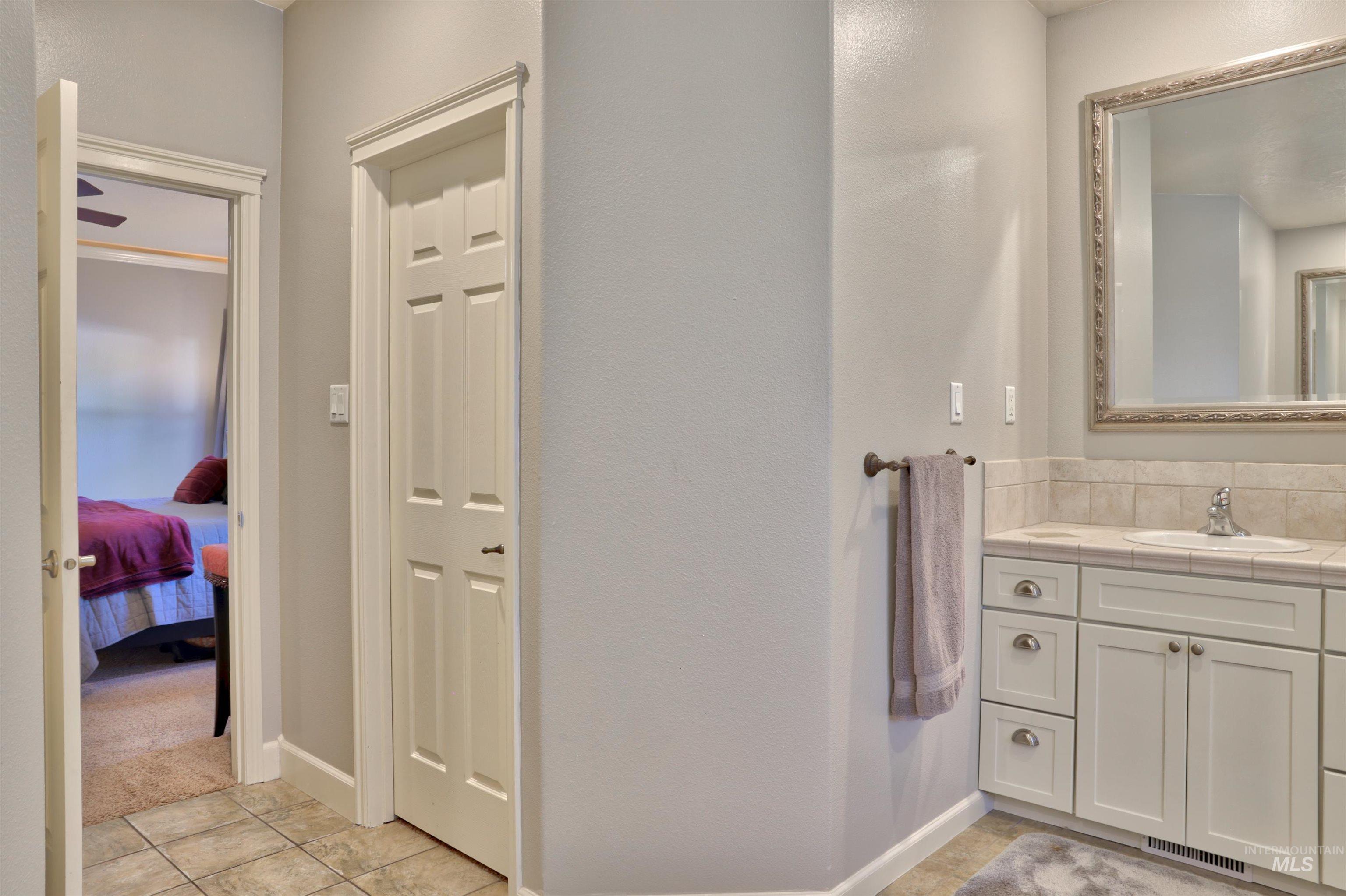 Ensuite bathroom featuring vanity, light tile patterned floors, and light carpet