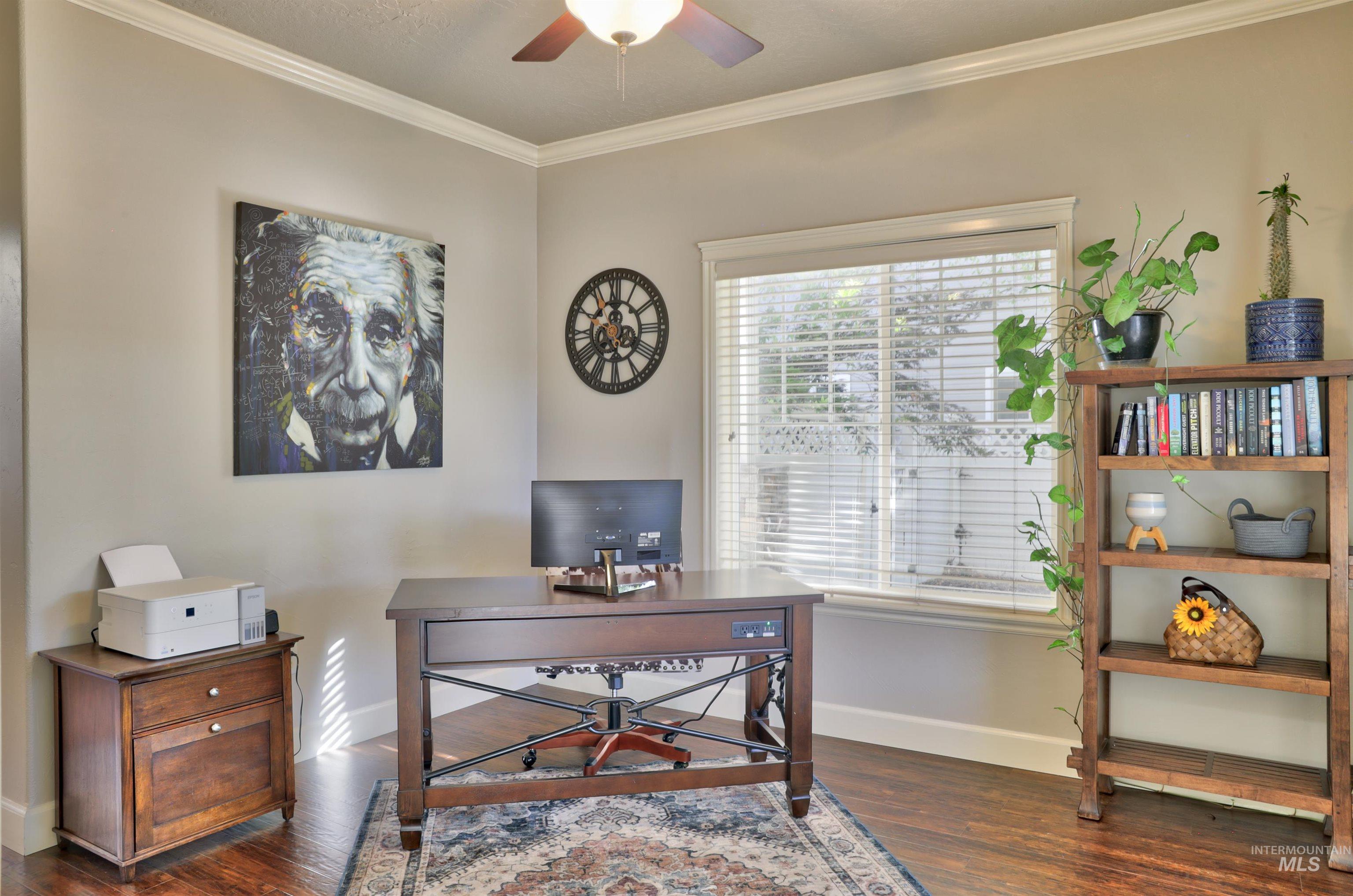 Home office with crown molding, dark wood-style flooring, and a ceiling fan
