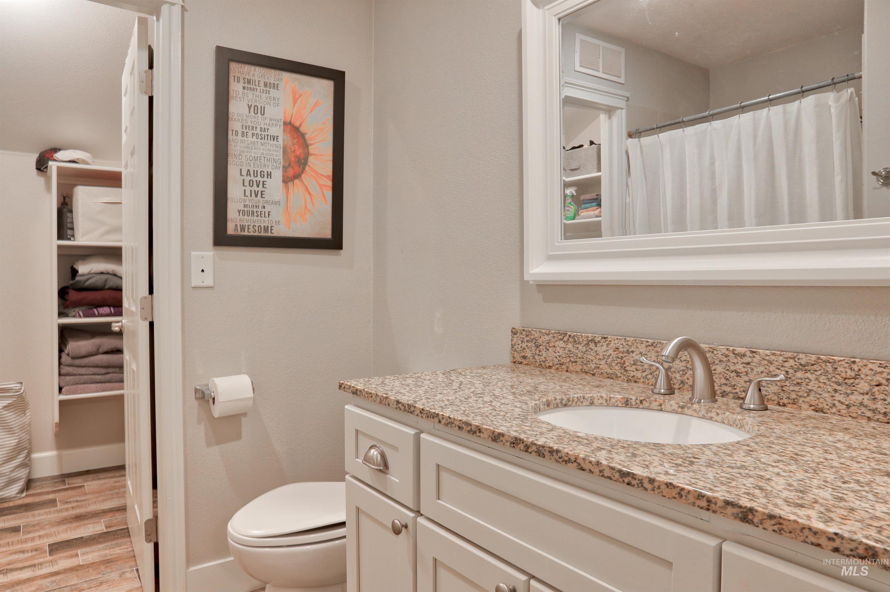 Full bath with vanity, light wood-style flooring, and curtained shower