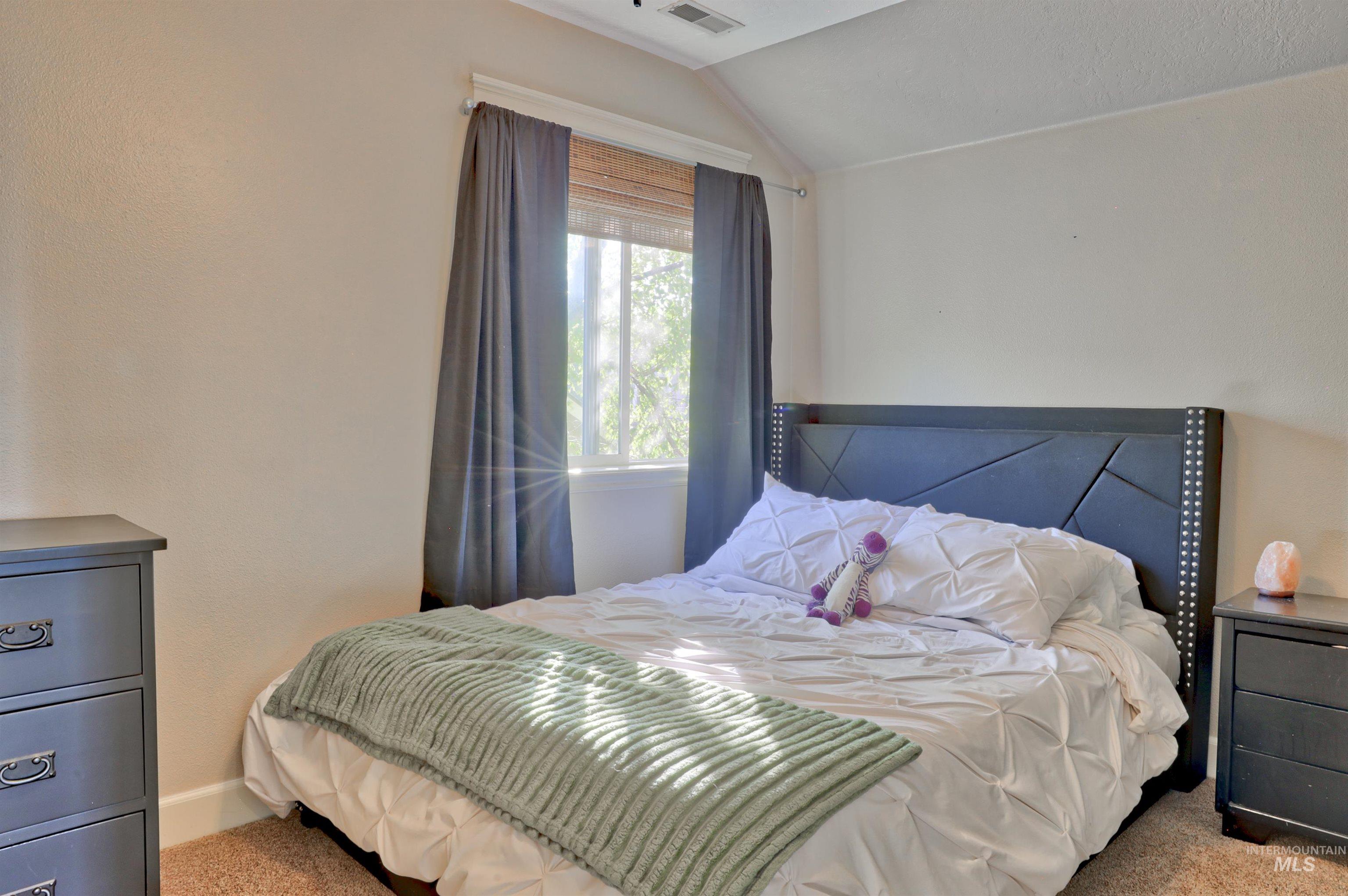 Carpeted bedroom featuring vaulted ceiling and baseboards