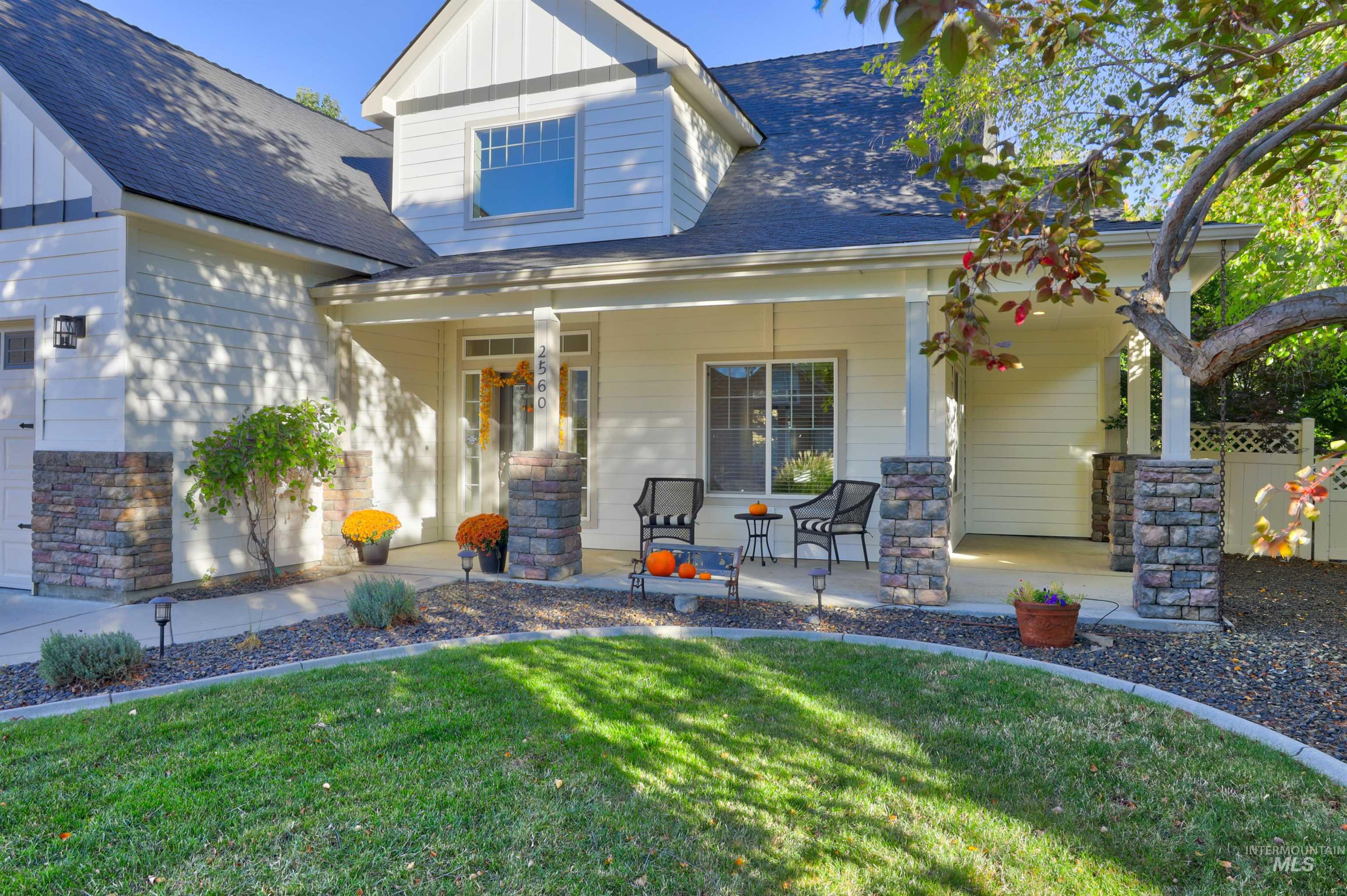 Doorway to property featuring roof with shingles, covered porch, a lawn, board and batten siding, and a garage