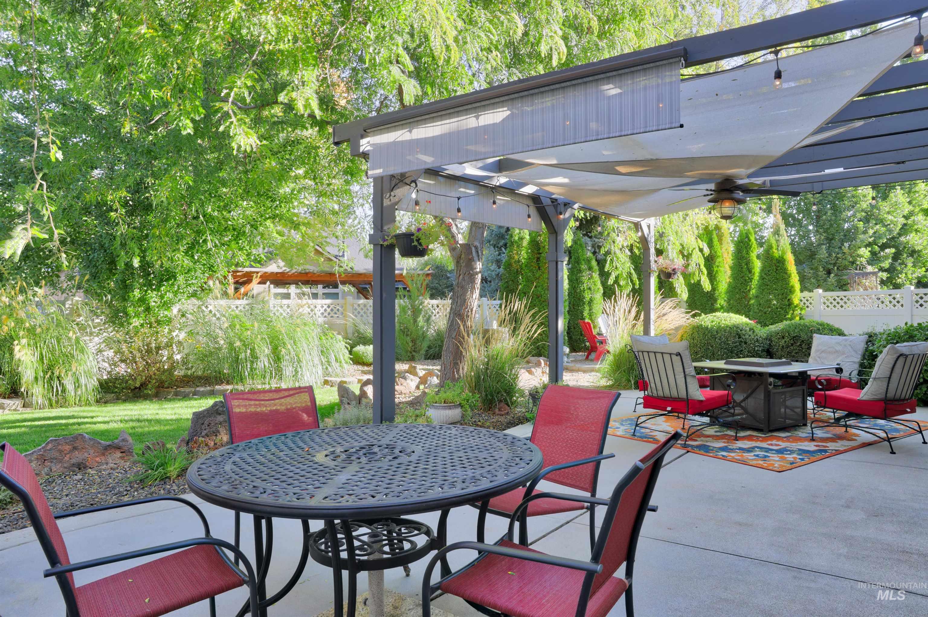 View of patio featuring a pergola, outdoor dining area, ceiling fan, and a fire pit
