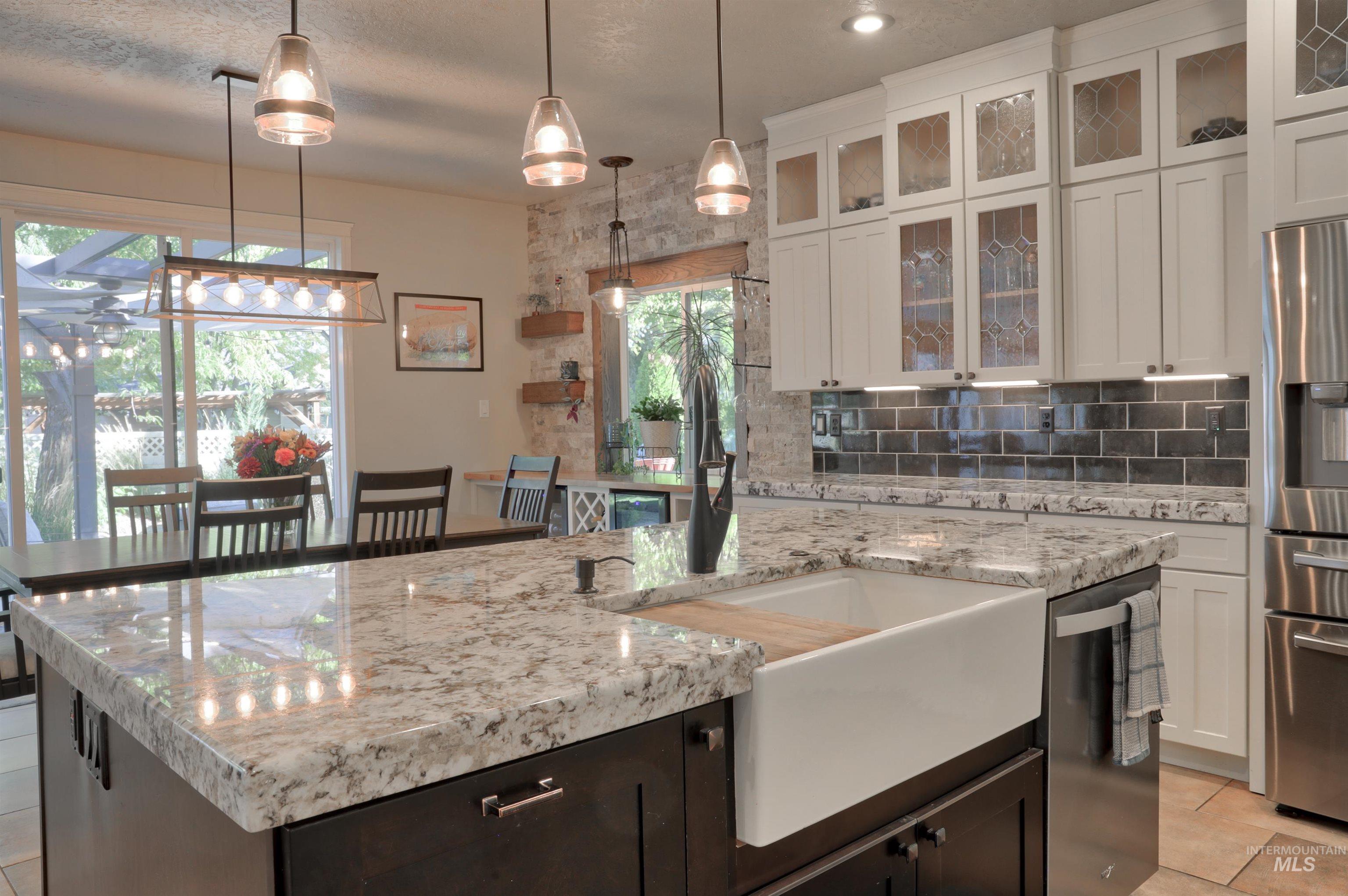 Kitchen with light tile patterned floors, tasteful backsplash, hanging light fixtures, and light stone counters