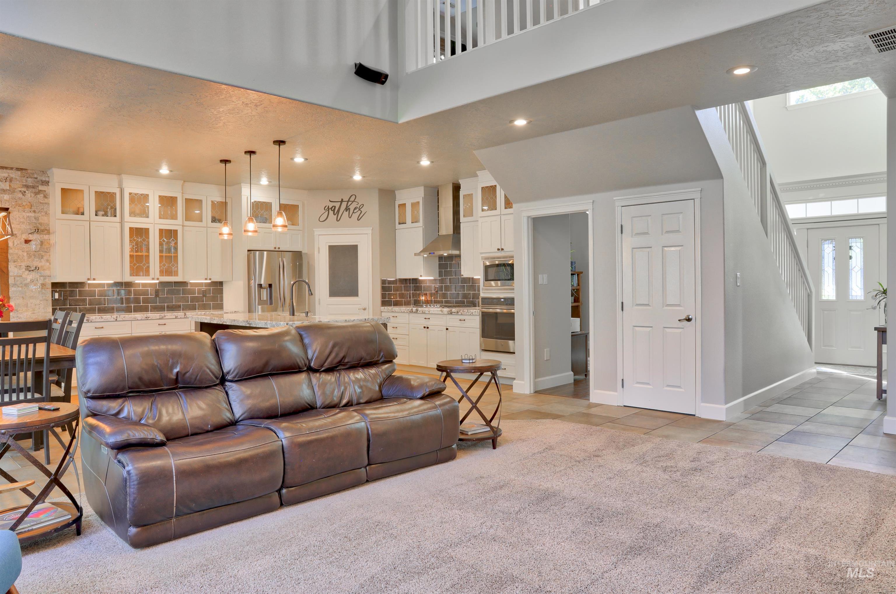Living room with light tile patterned floors, a high ceiling, light carpet, and recessed lighting