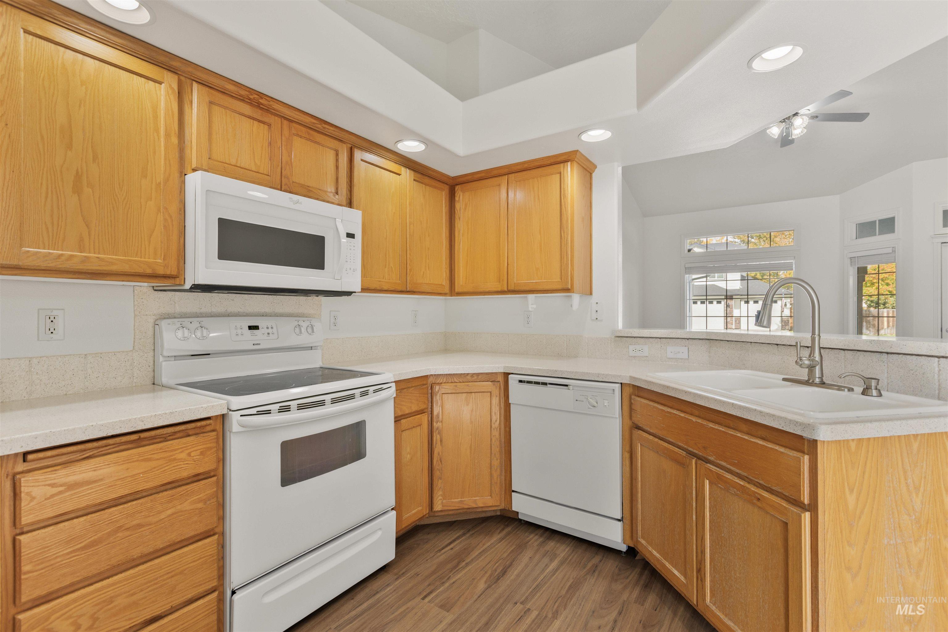 Kitchen with white appliances, recessed lighting, a peninsula, light wood-type flooring, and ceiling fan
