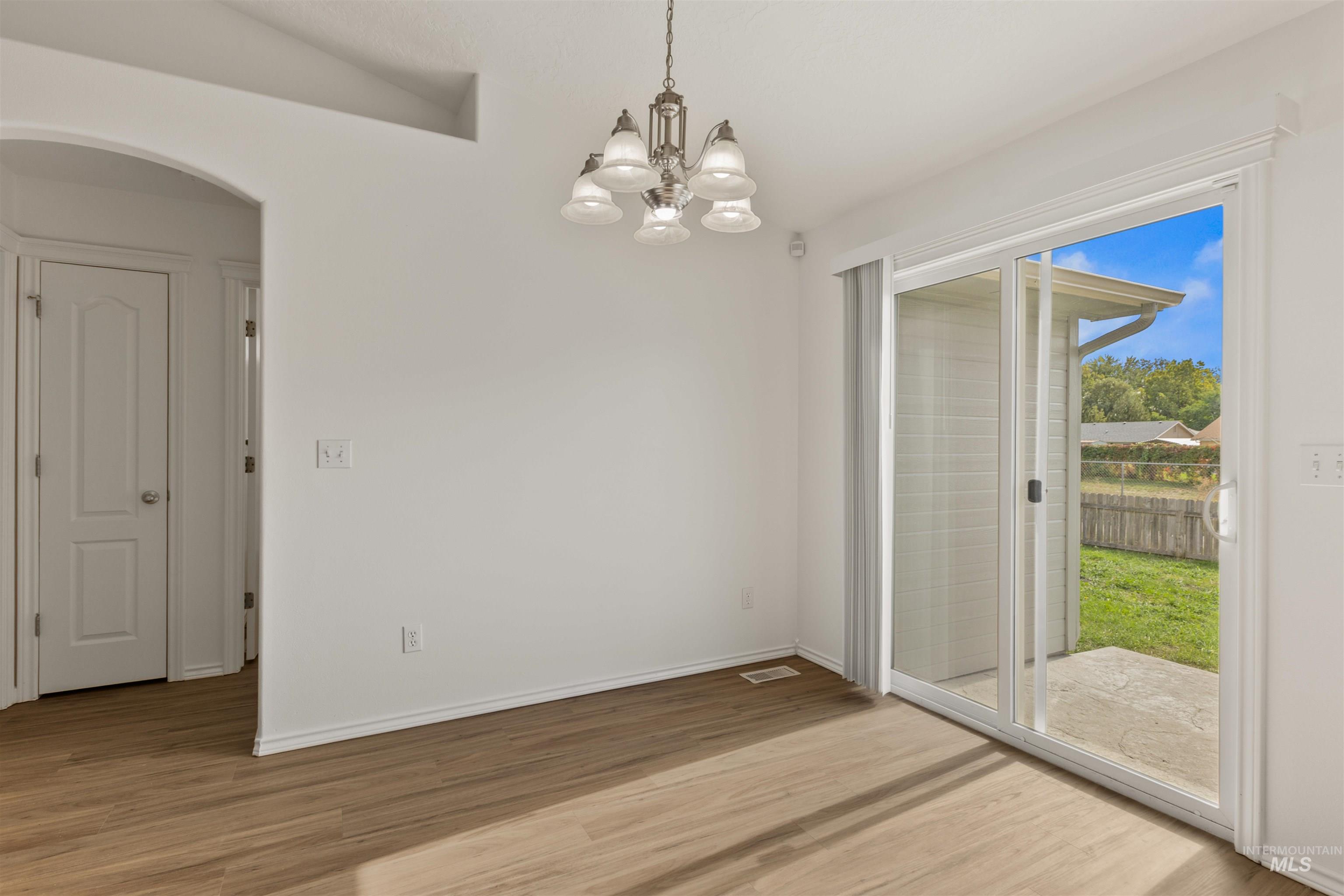 Unfurnished dining area with light wood finished floors, a chandelier, and arched walkways