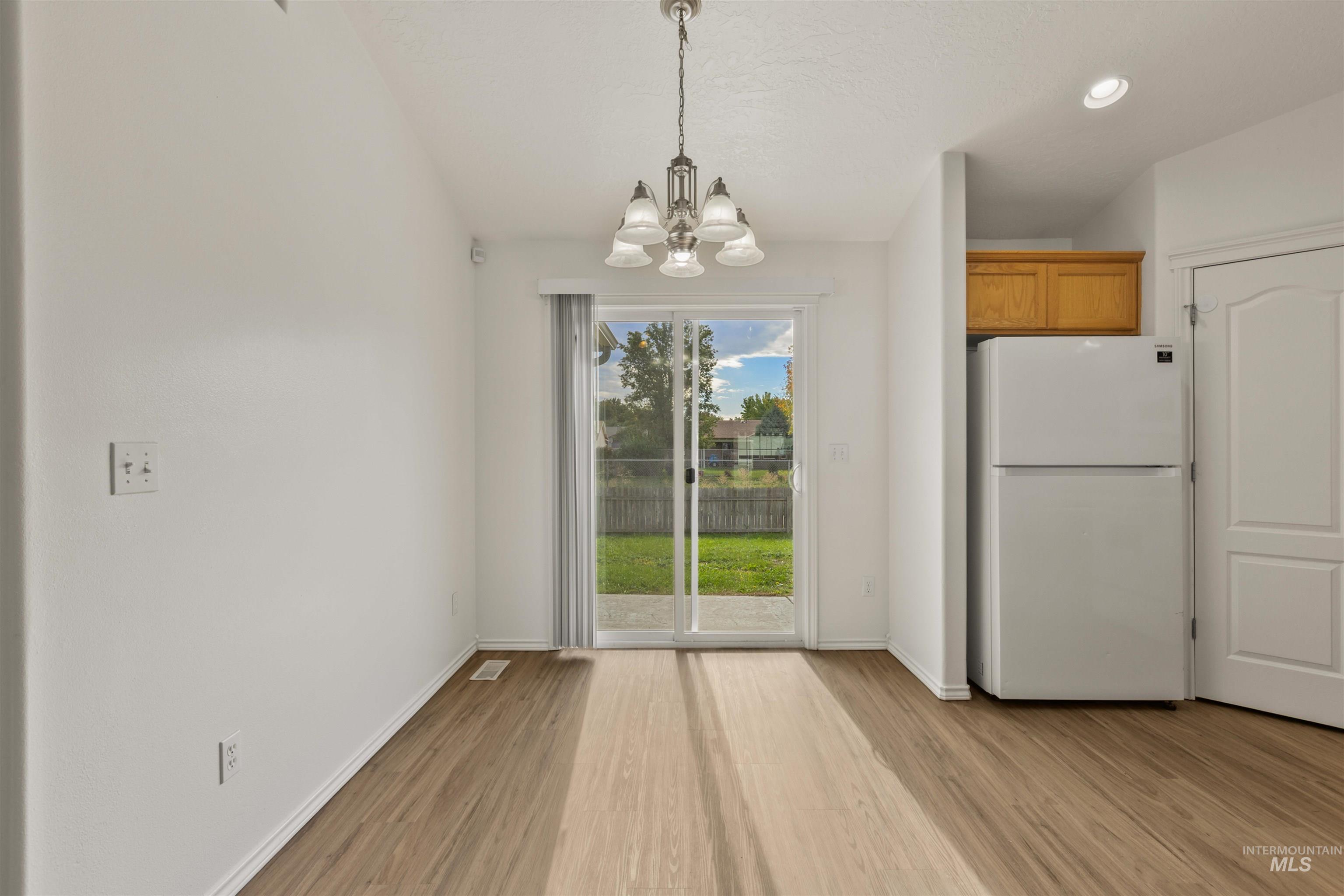 Unfurnished dining area with light wood-style flooring, a chandelier, and recessed lighting