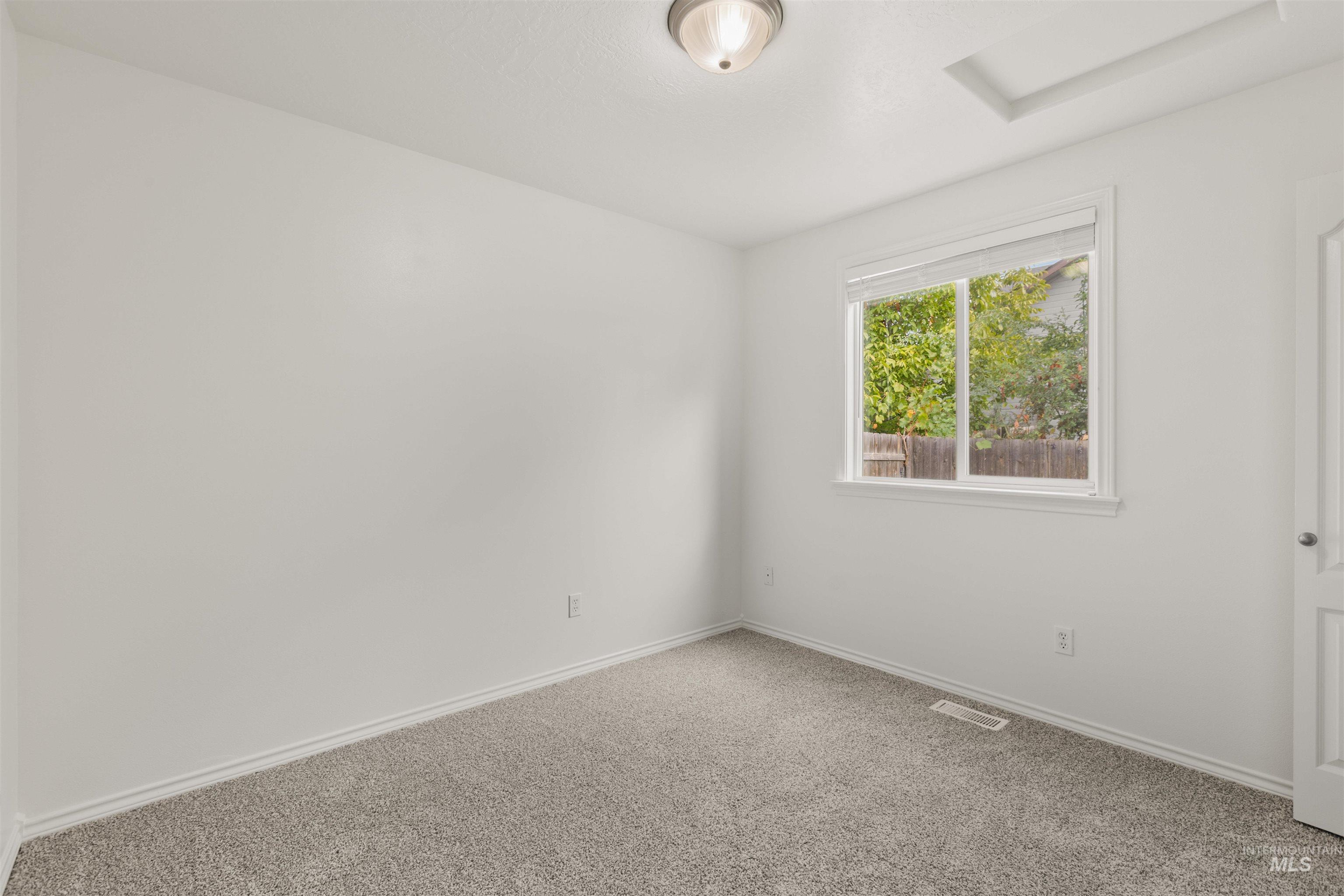 Empty room featuring carpet and attic access