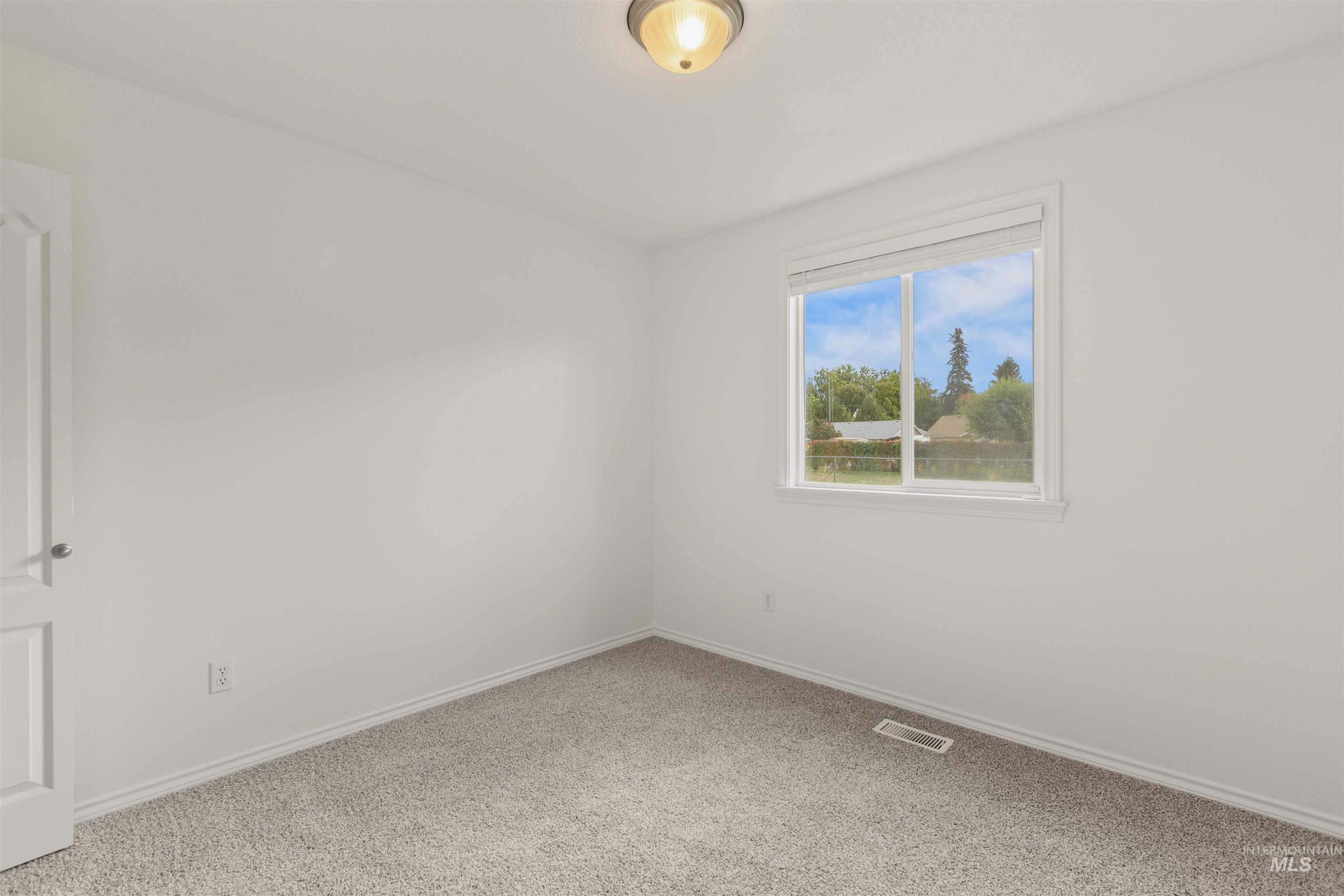 Carpeted spare room featuring baseboards